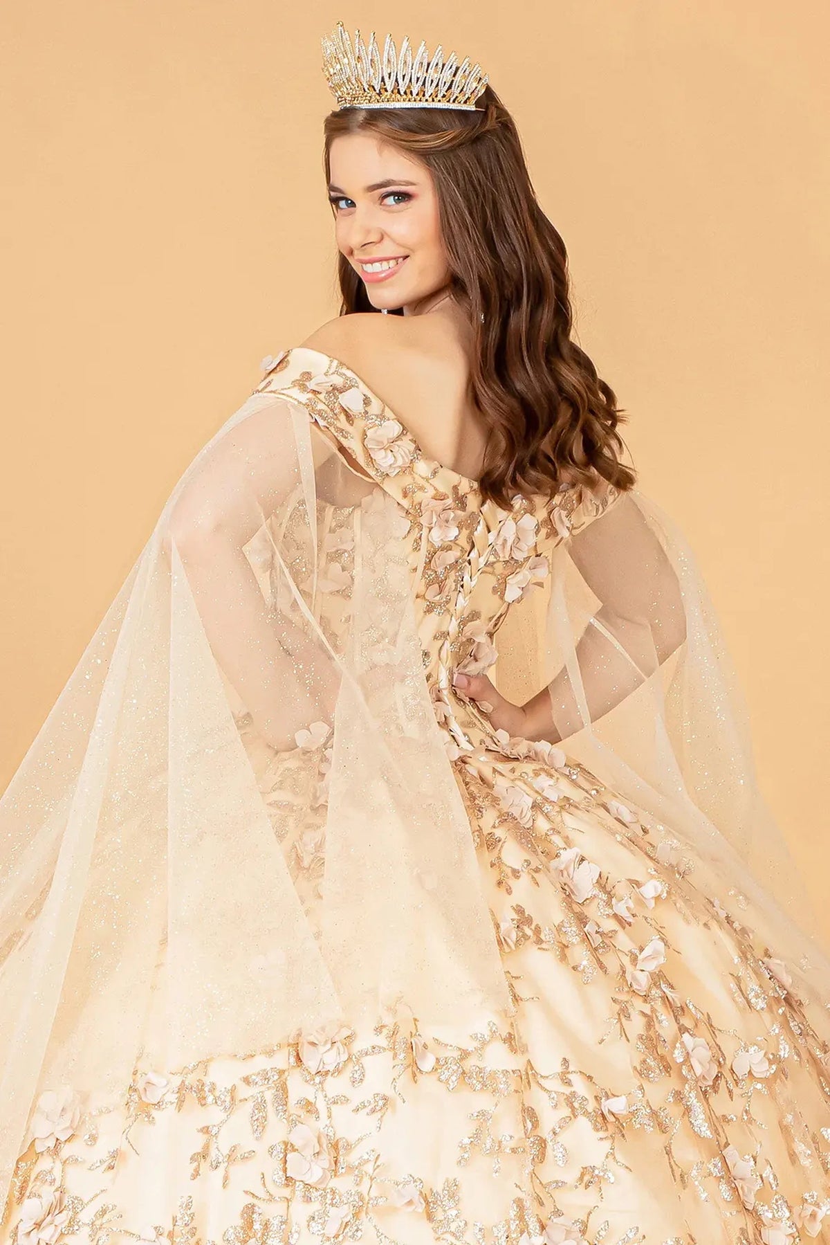 Layered skirt showcases the Champagne quinceañera ball gown with 3d floral appliqués.