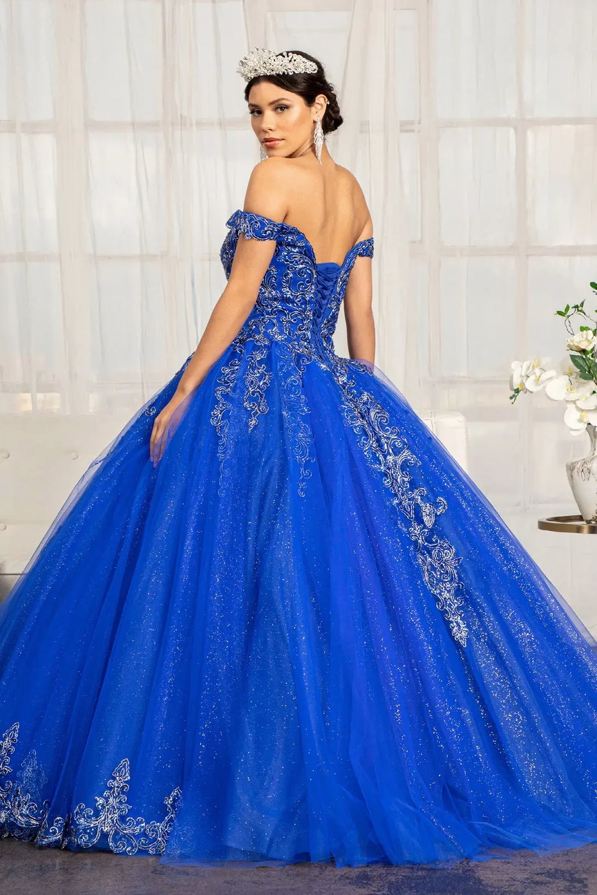 Bodice close-up highlights the Royal Blue quinceañera ball gown with cutaway shoulder detail.