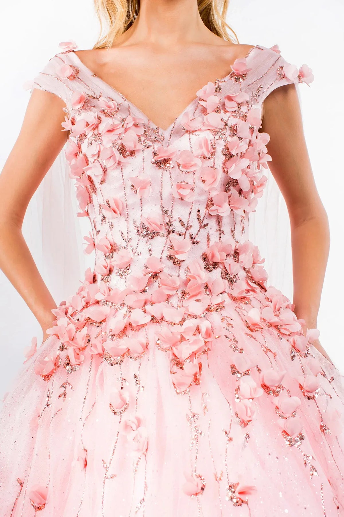 Layered skirt showcases the Blush quinceañera ball gown with detachable cape sleeves.