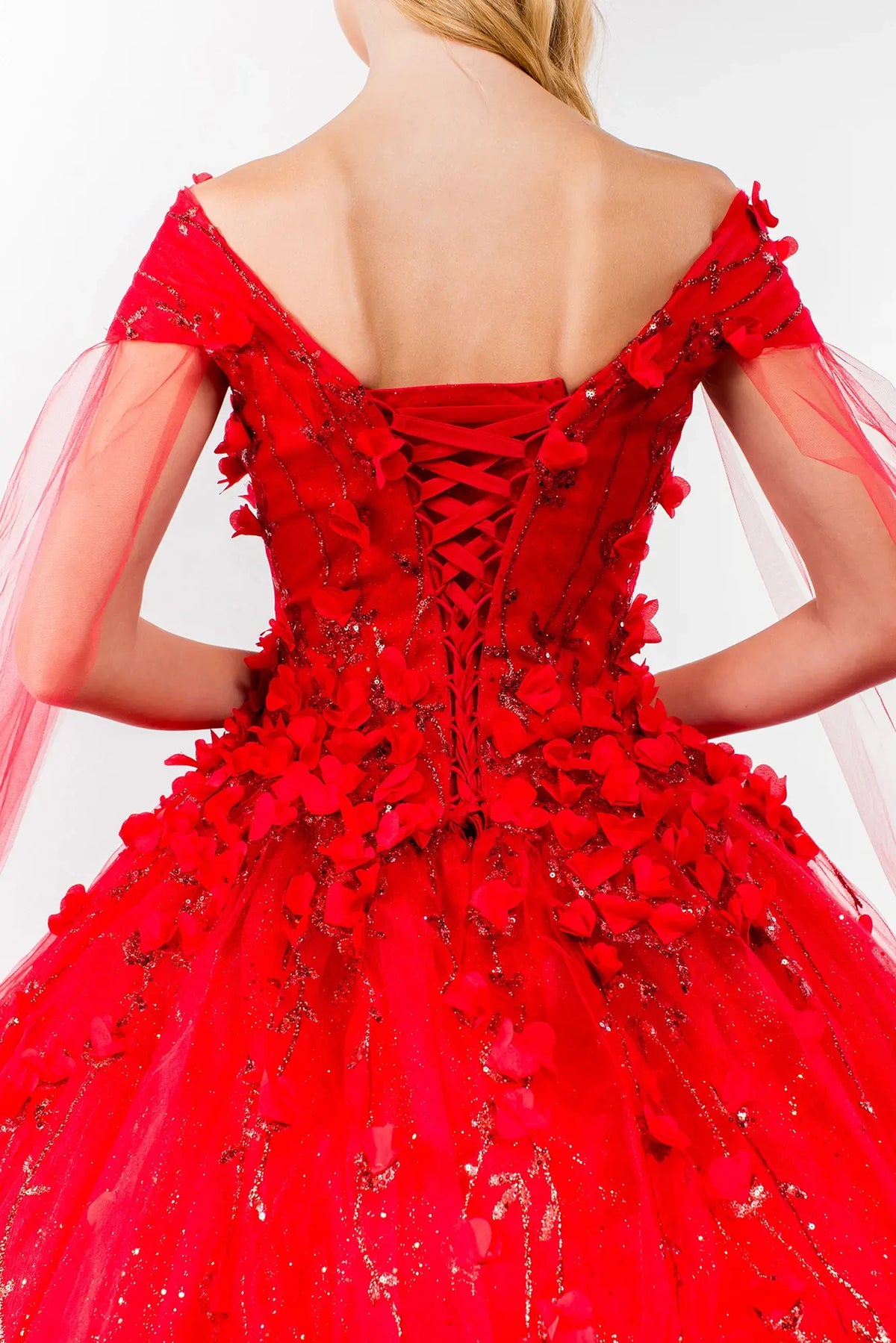 Layered skirt showcases the Red quinceañera ball gown with detachable cape sleeves.