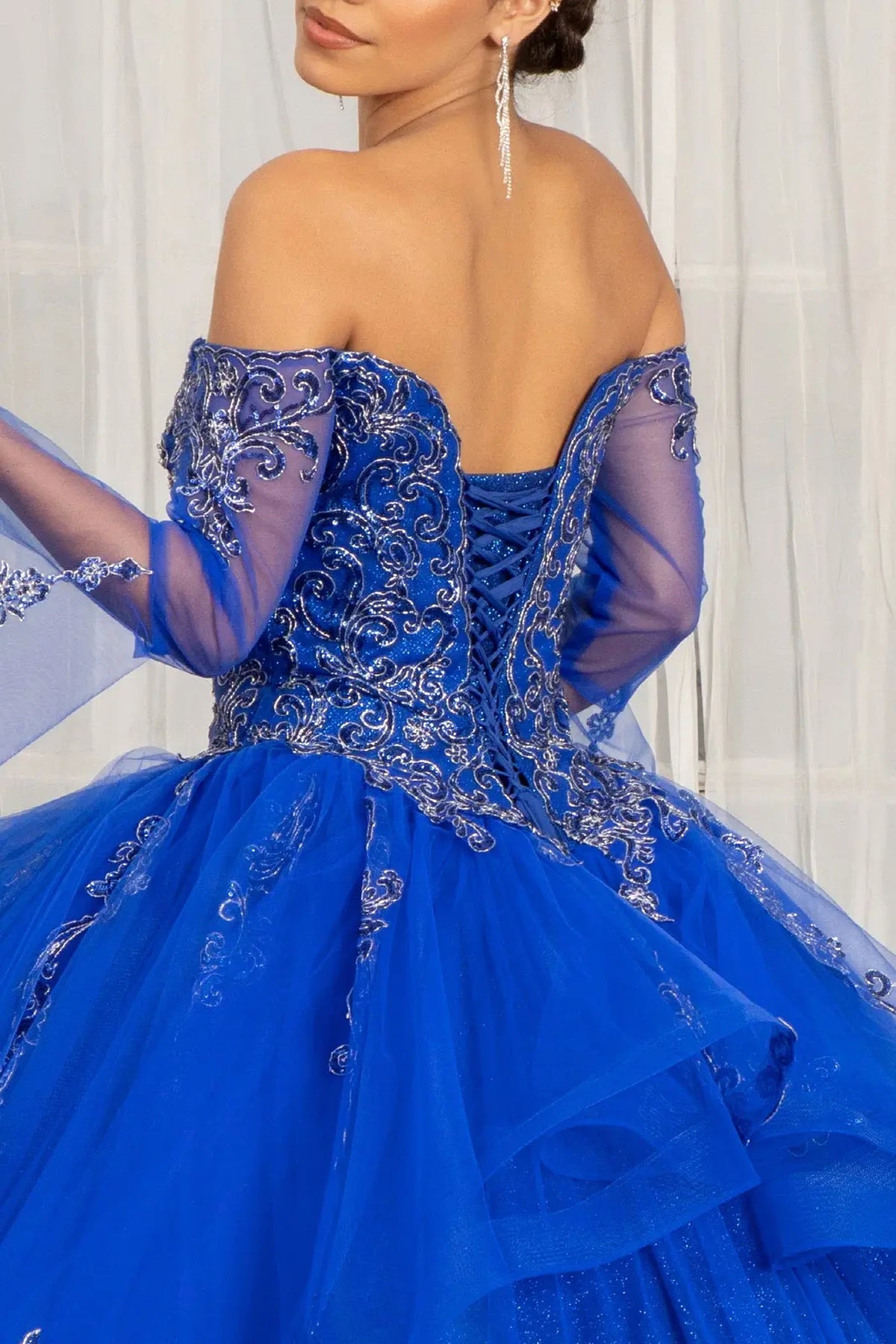 Embroidered details frame the Royal Blue quinceañera ball gown with long mesh sleeves.