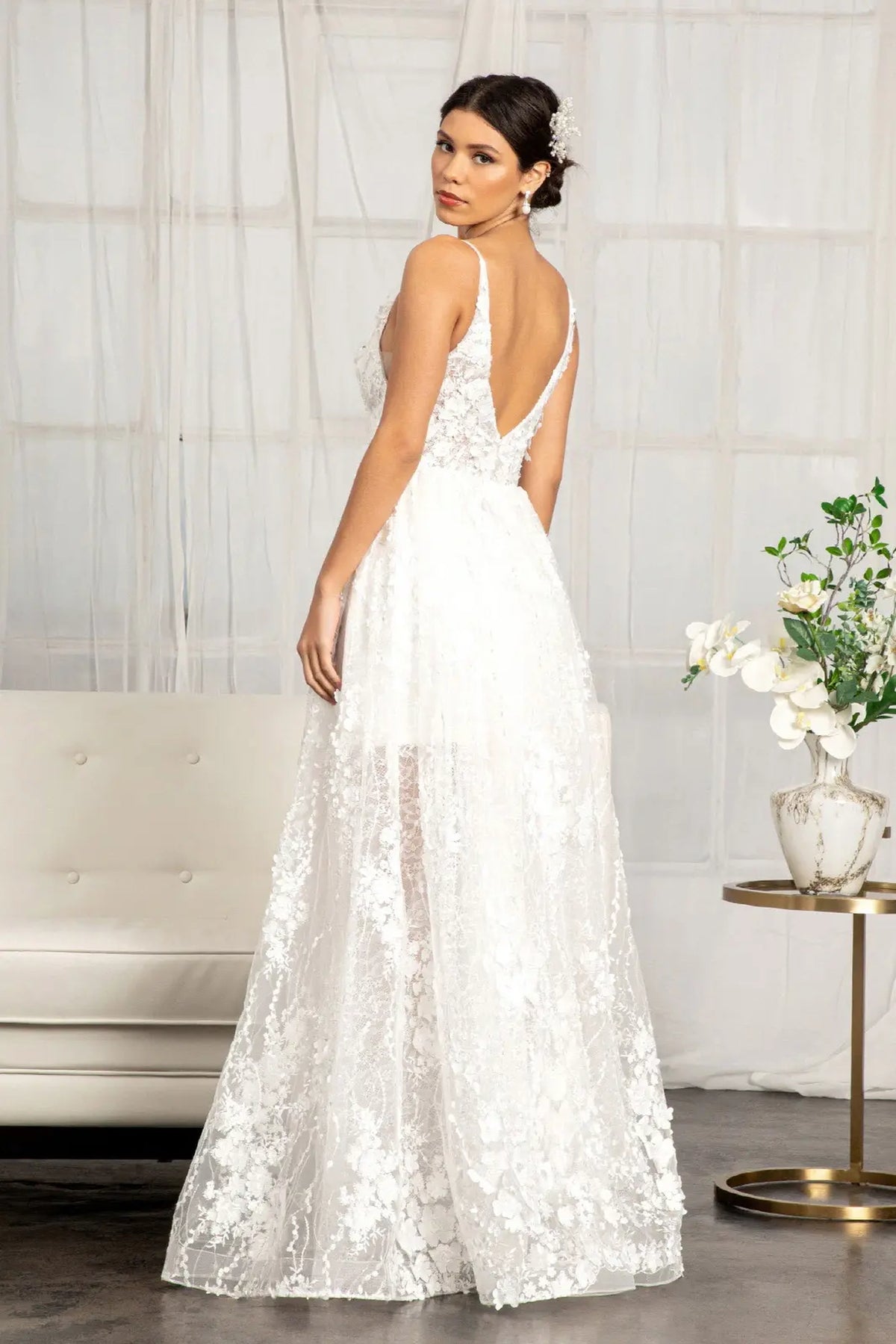 The white wedding gown's open V-back falls into a softly embroidered A-line skirt.