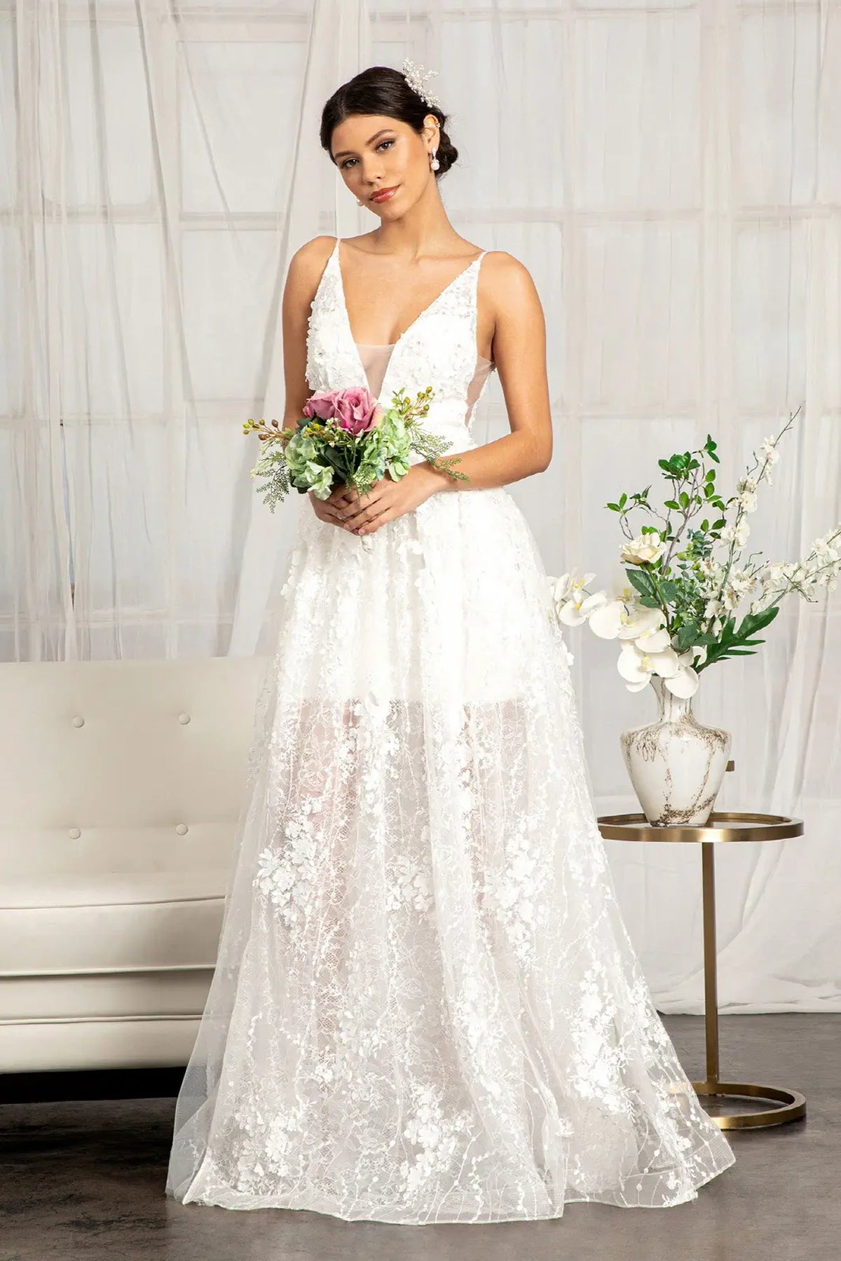 Three-dimensional blossoms continue into the flowing skirt of this white wedding gown.