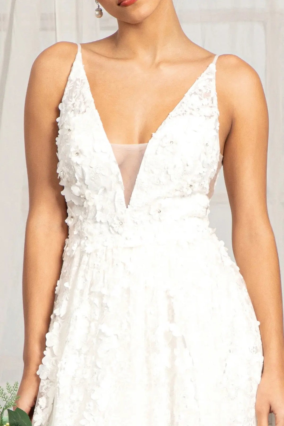 Raised floral appliques border the illusion V-neckline on the white wedding gown.
