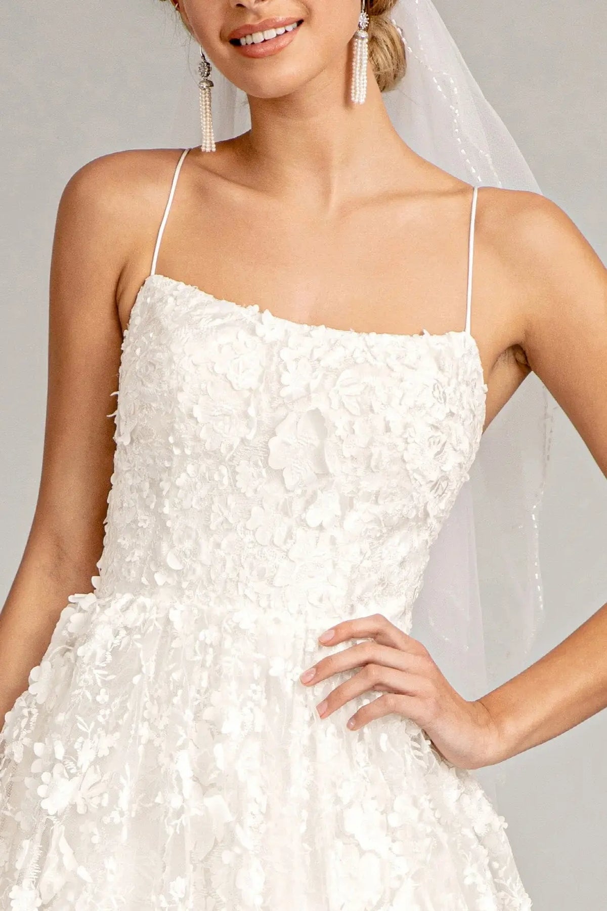White wedding gown with floral appliques across its straight-across mesh bodice.