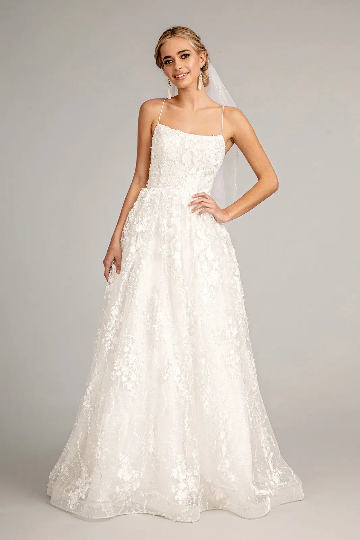 Airy floral embroidery spreads through the A-line skirt of this white wedding gown.
