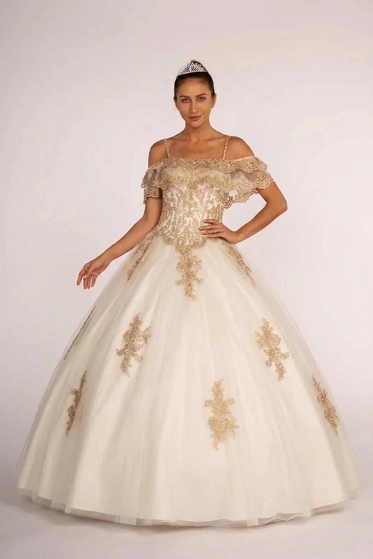 Displayed in full, the Off White quinceañera ball gown features gold floral appliqué over an off-shoulder ivory ball skirt.