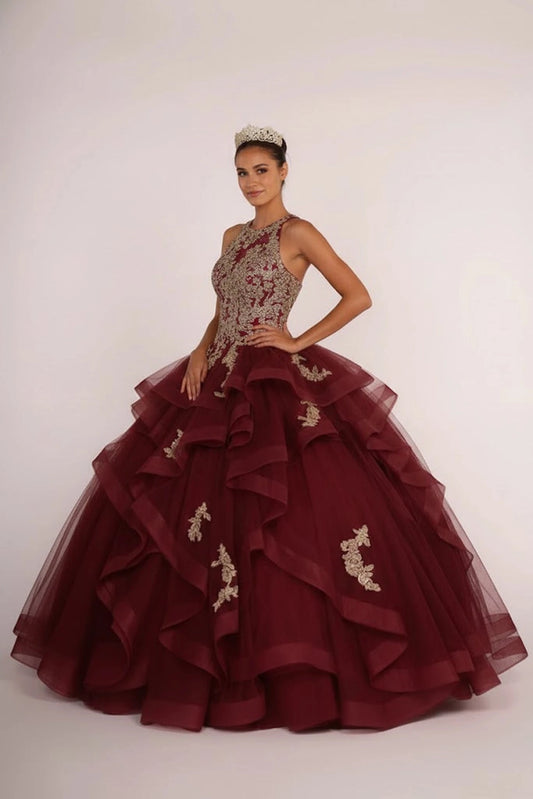 Displayed in full, the Burgundy quinceañera ball gown features a gold halter bodice and burgundy tiered skirt with appliqué.