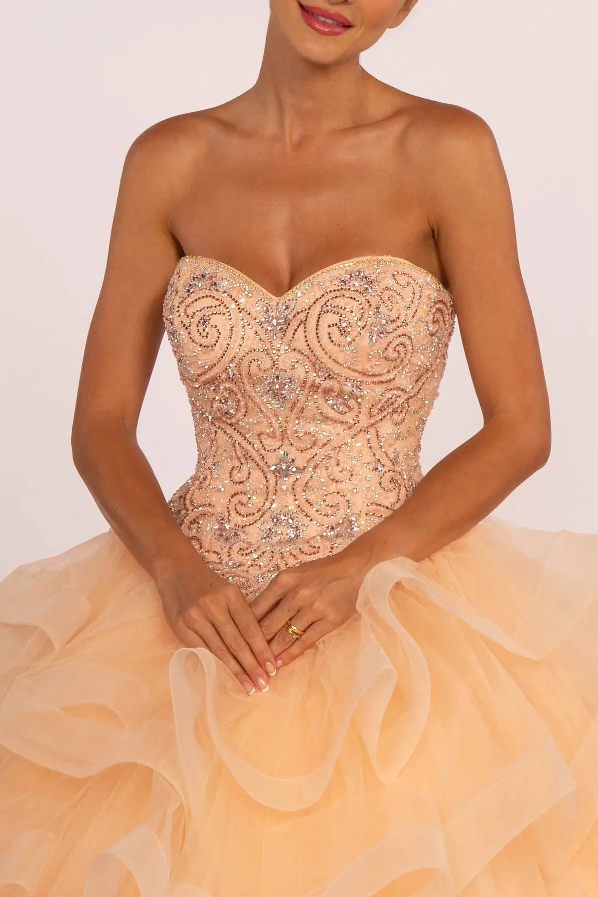 Bodice close-up highlights the Peach quinceañera ball gown with ruffled tulle skirt.