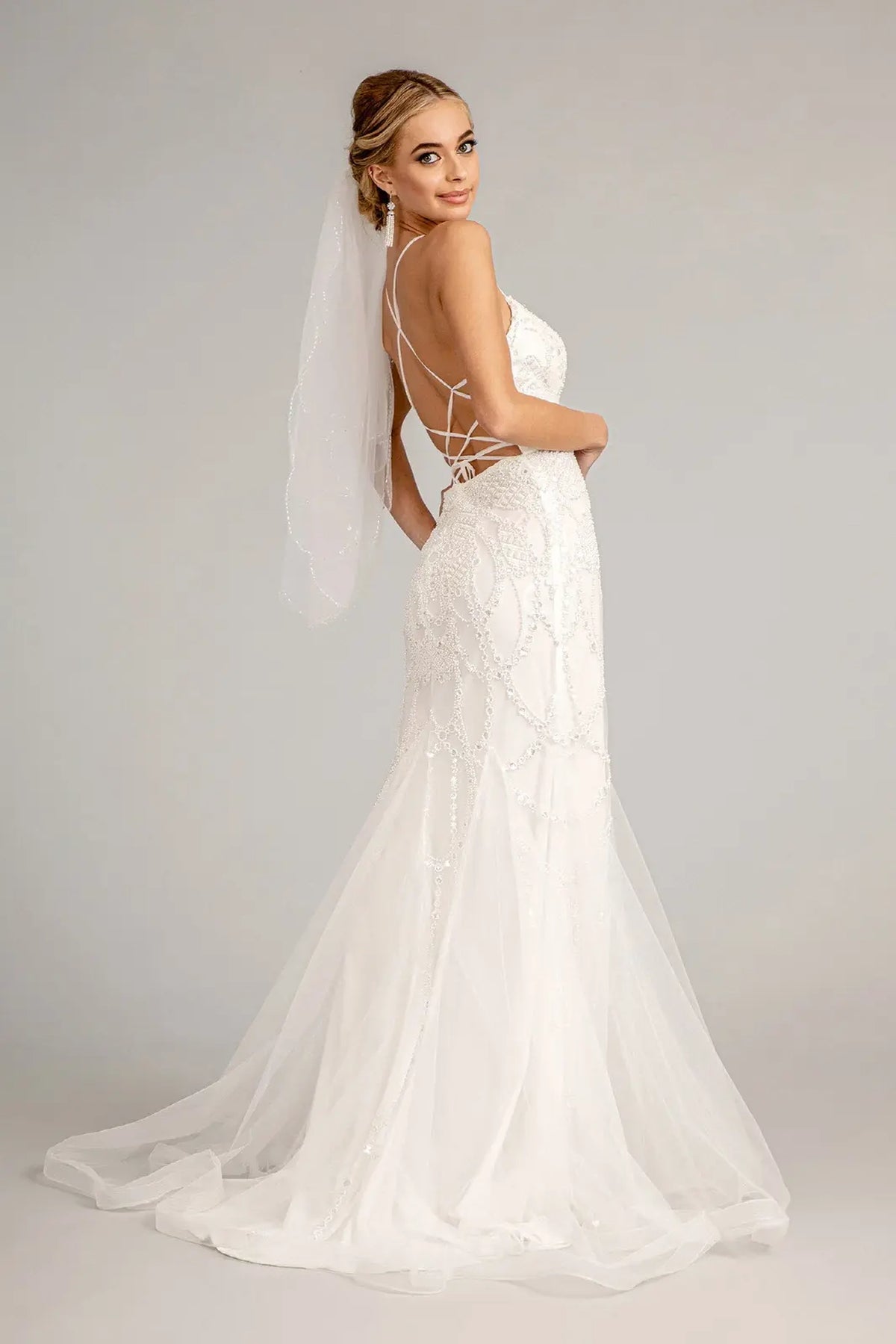 Strappy corset lacing sits above the sweeping train of the ivory wedding gown.