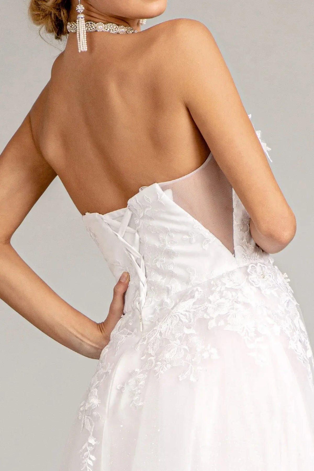 Ribbon lacing fastens the sheer floral bodice at the back of this white wedding gown.