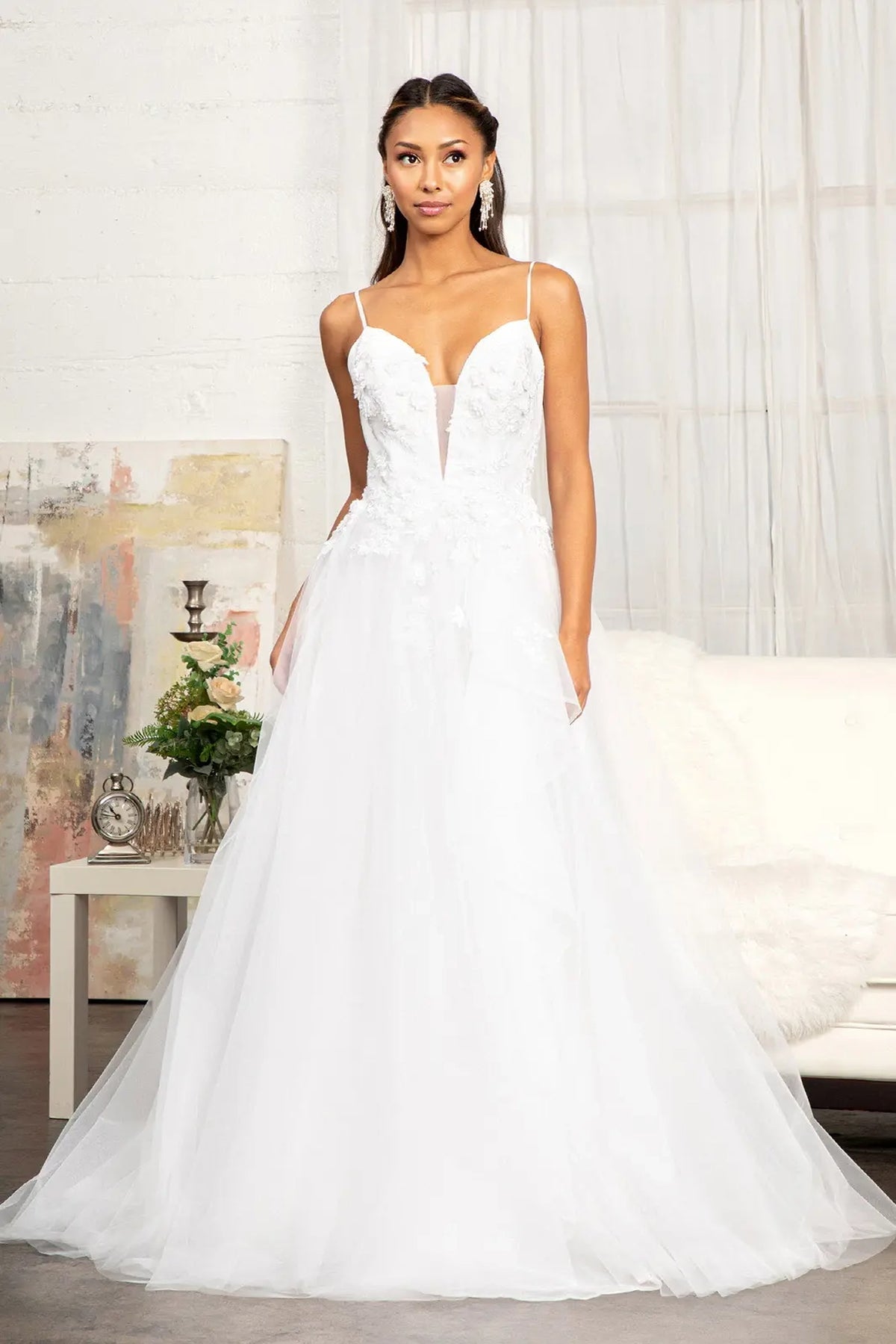 An airy A-line skirt flows beneath the floral appliques of this white wedding gown.