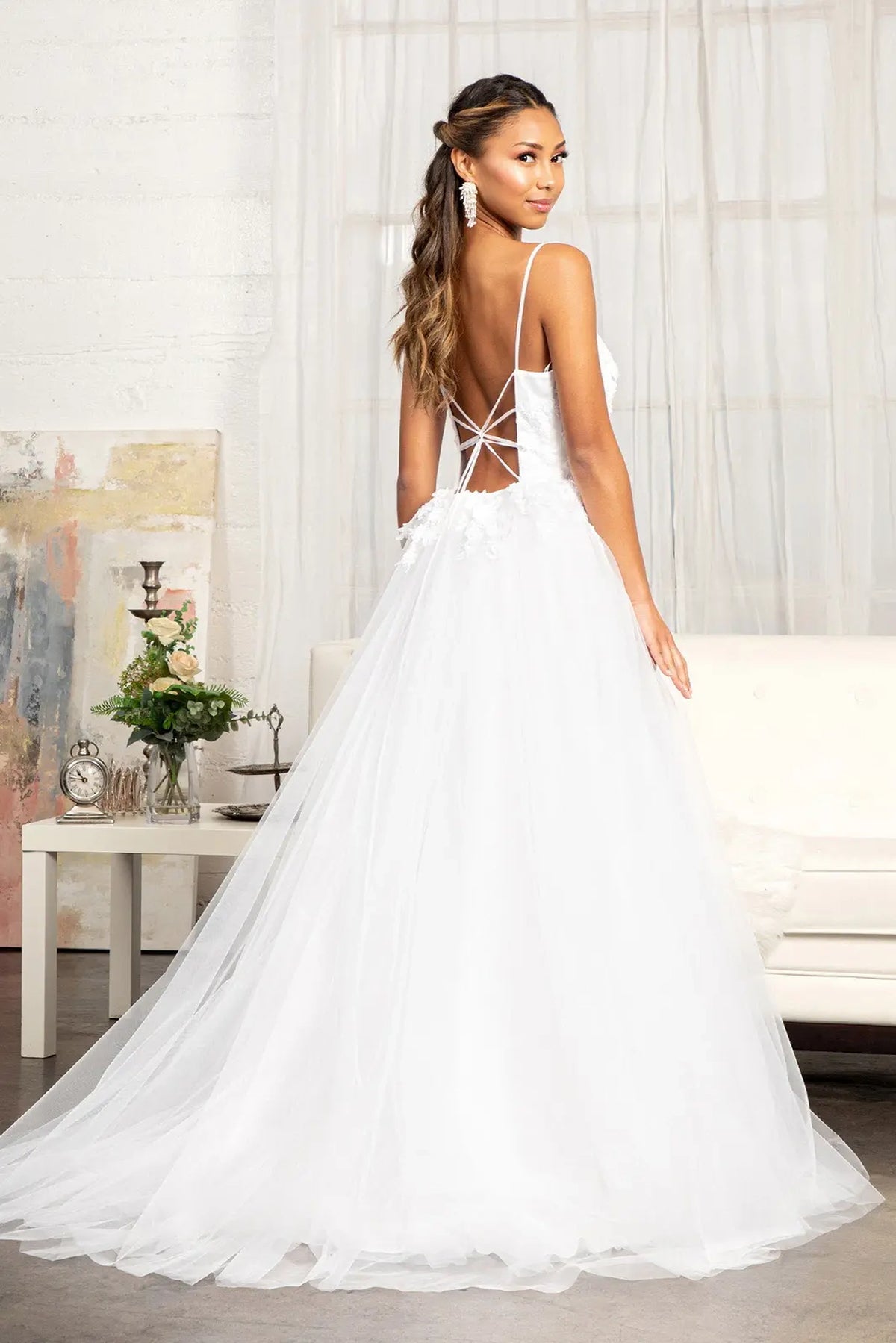 Decorative corset lacing frames the open back of the white wedding gown.