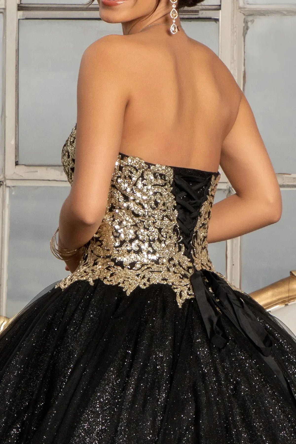 Embroidered details frame the Black quinceañera ball gown with gold sequin embellishment.
