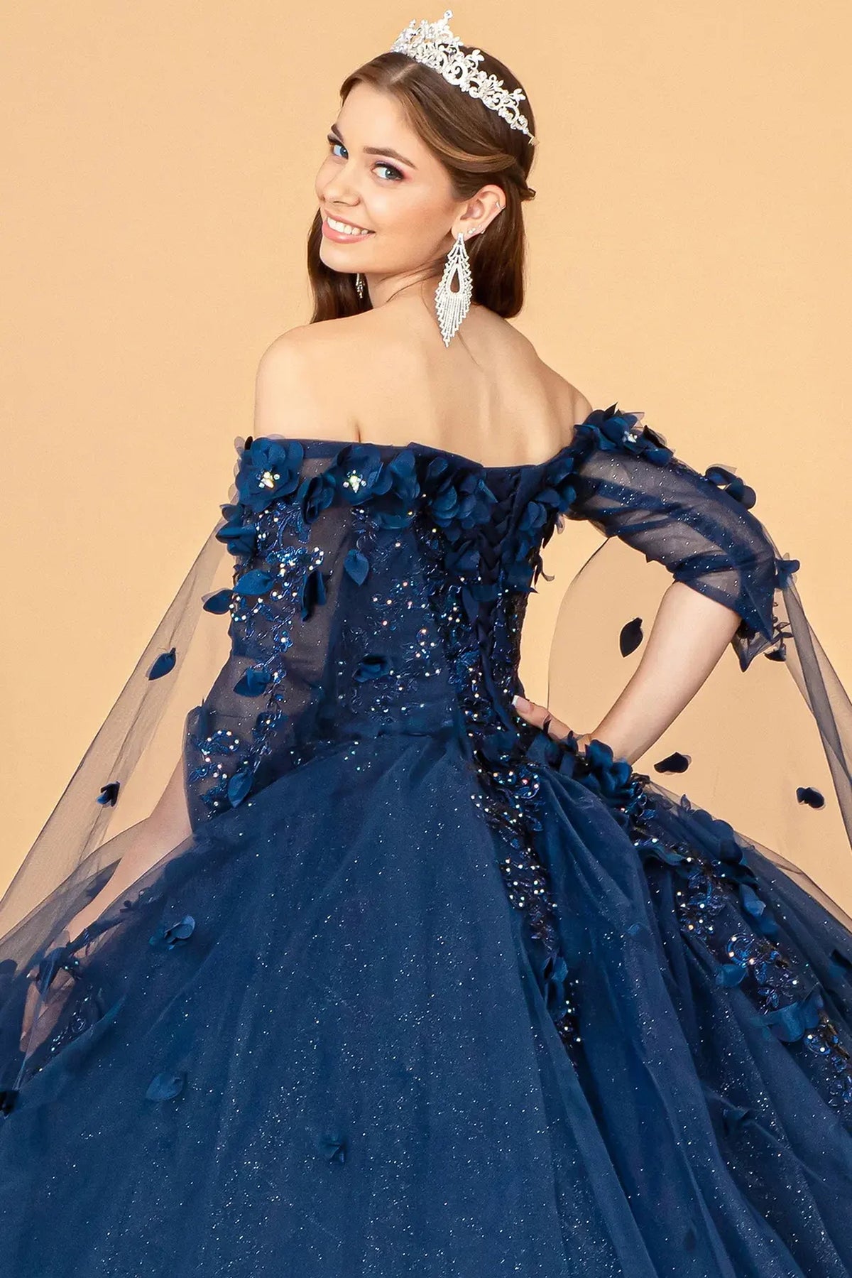 Layered skirt showcases the Navy quinceañera ball gown with shoulder mesh drapes.