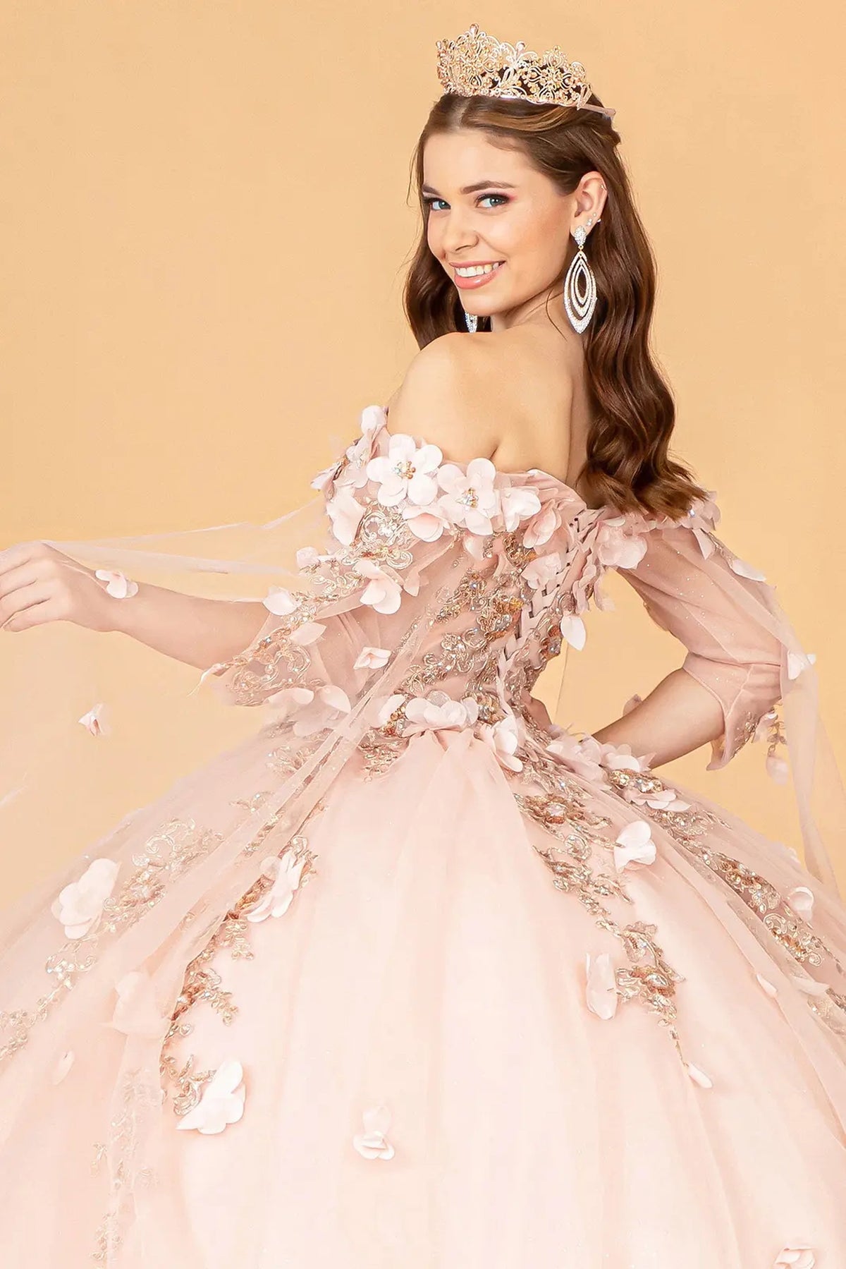Layered skirt showcases the Rose Gold quinceañera ball gown with shoulder mesh drapes.