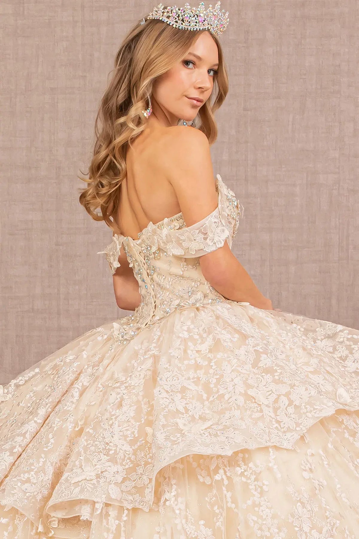 Layered skirt showcases the Champagne quinceañera ball gown with 3d butterfly appliqués.
