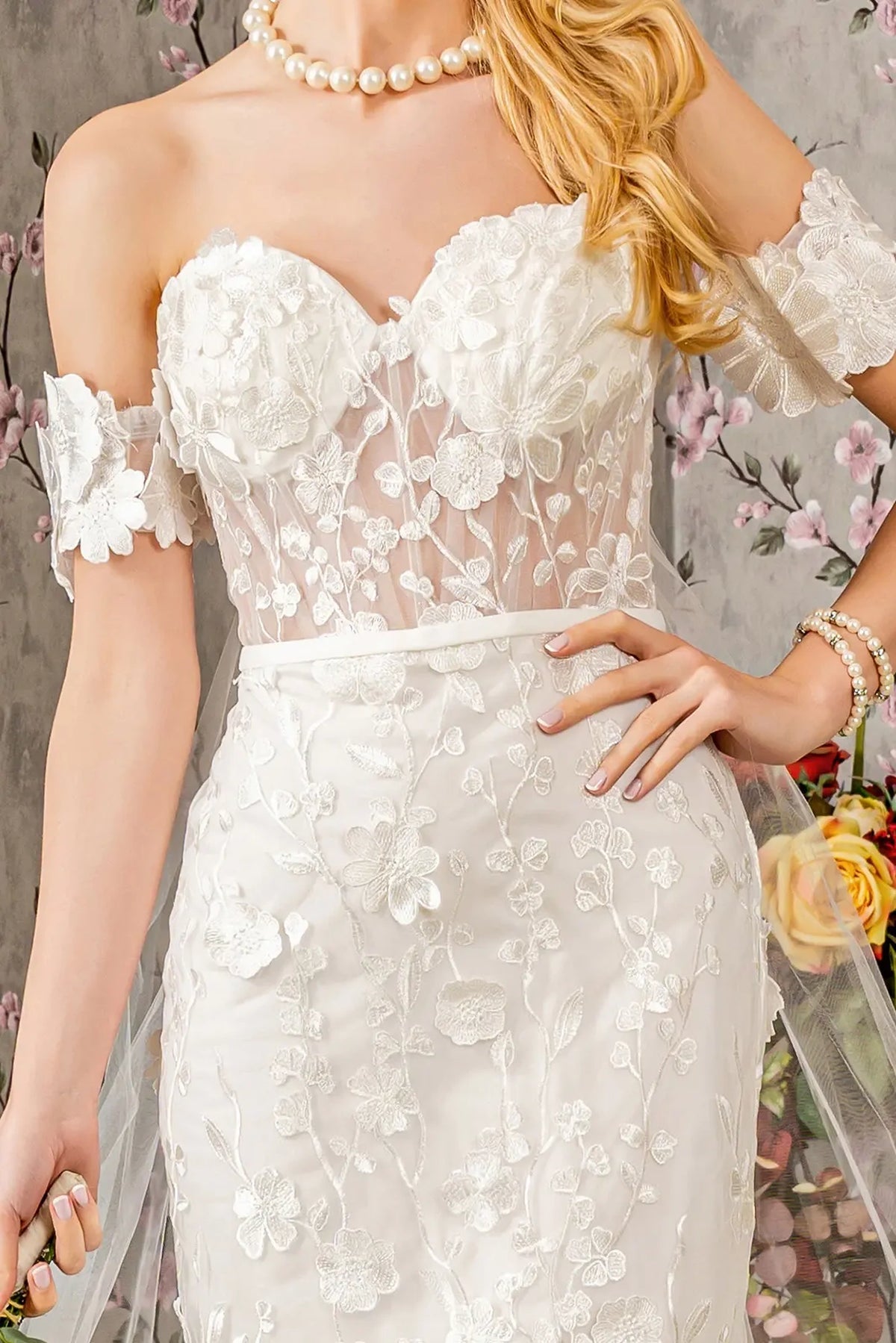 Ivory wedding gown with dimensional flowers on a sheer sweetheart bodice and shoulder bands.