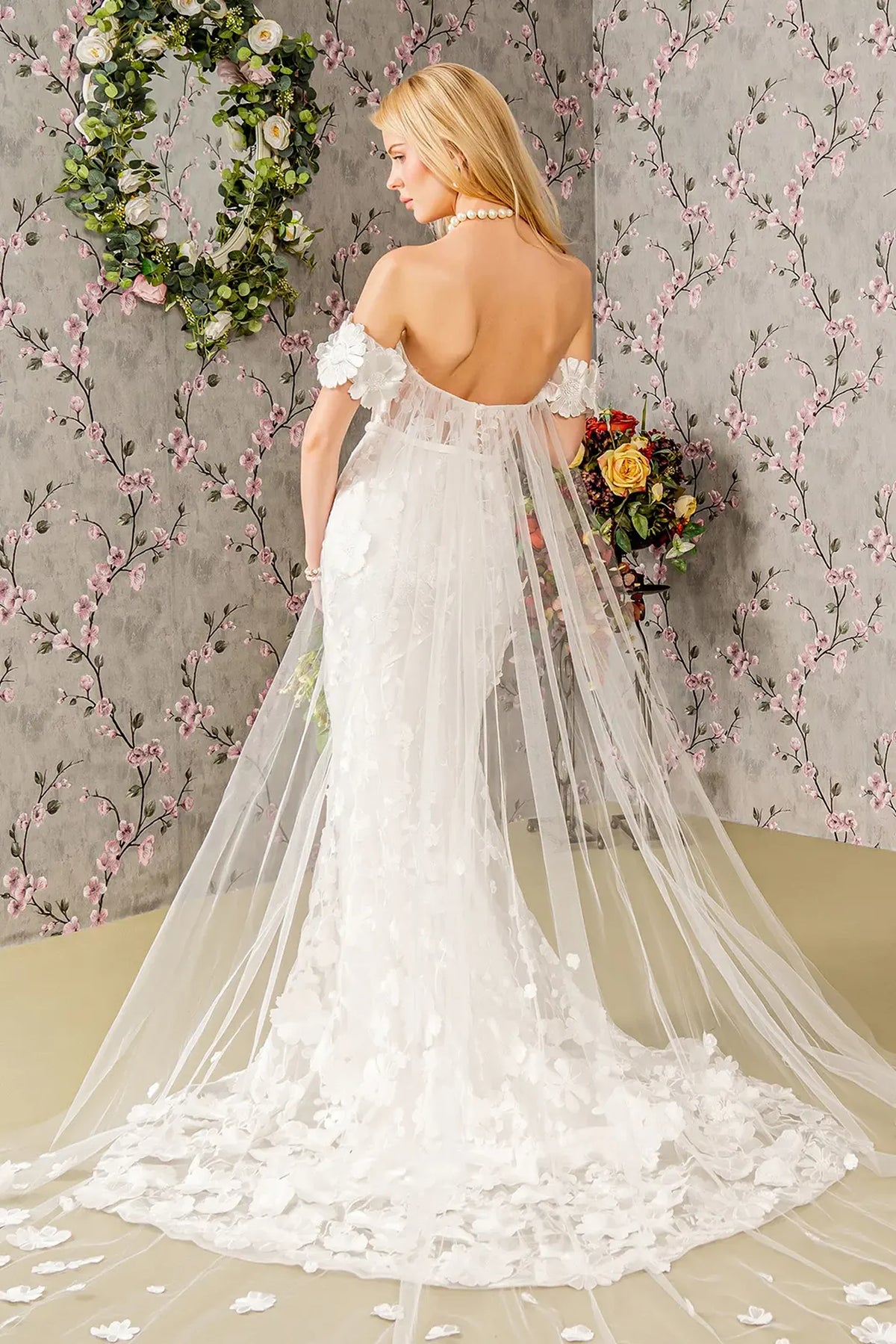 A long sheer drape flows from the open back of the ivory wedding gown.