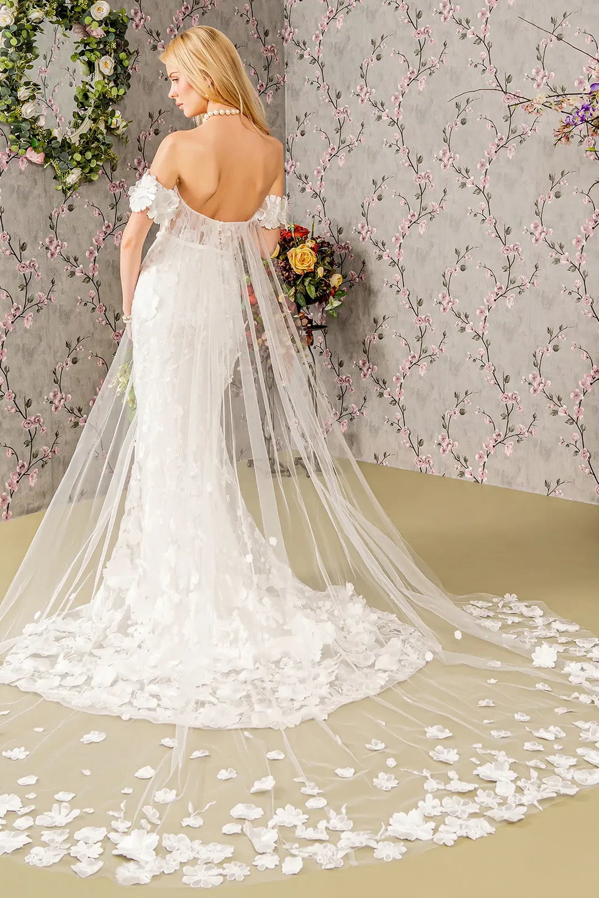 Scattered floral appliques decorate the trailing mesh drape on this ivory wedding gown.