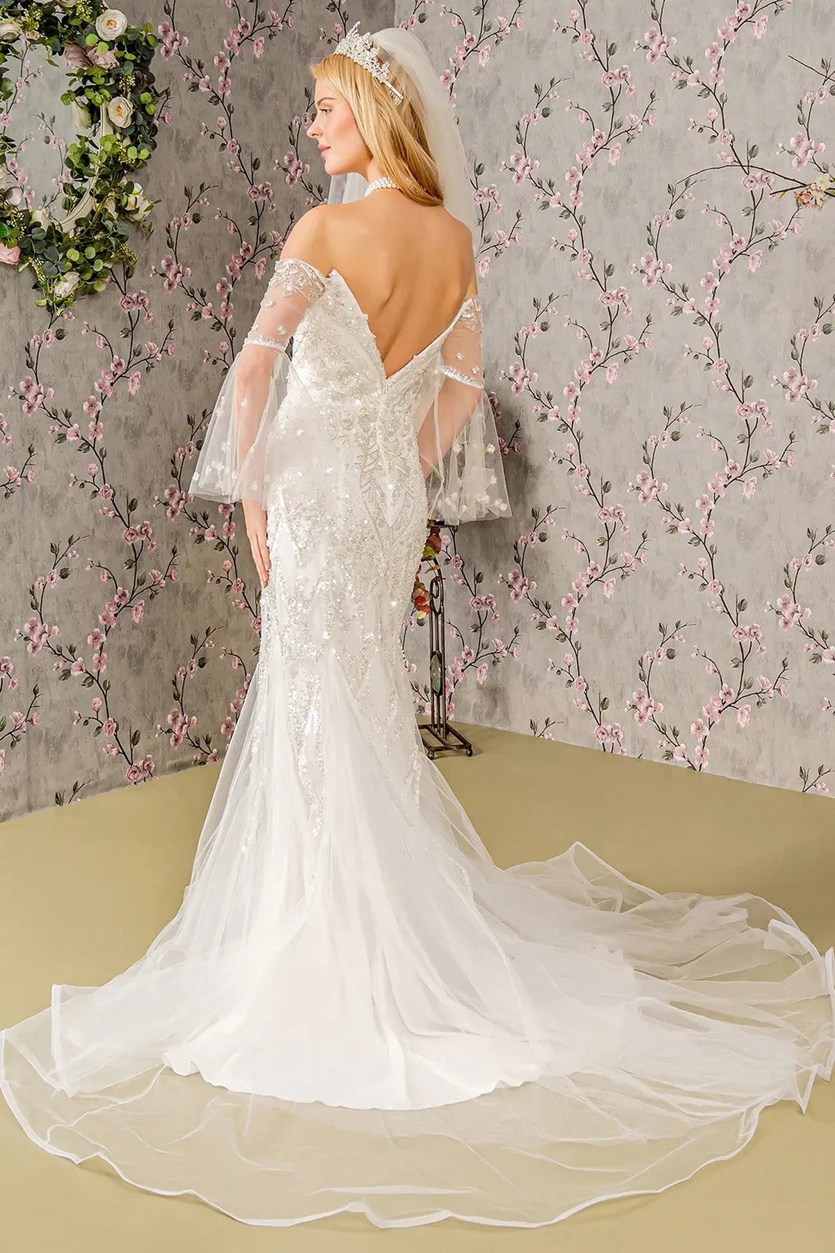 The low V-back flows into a sweeping mesh train on the ivory wedding gown.