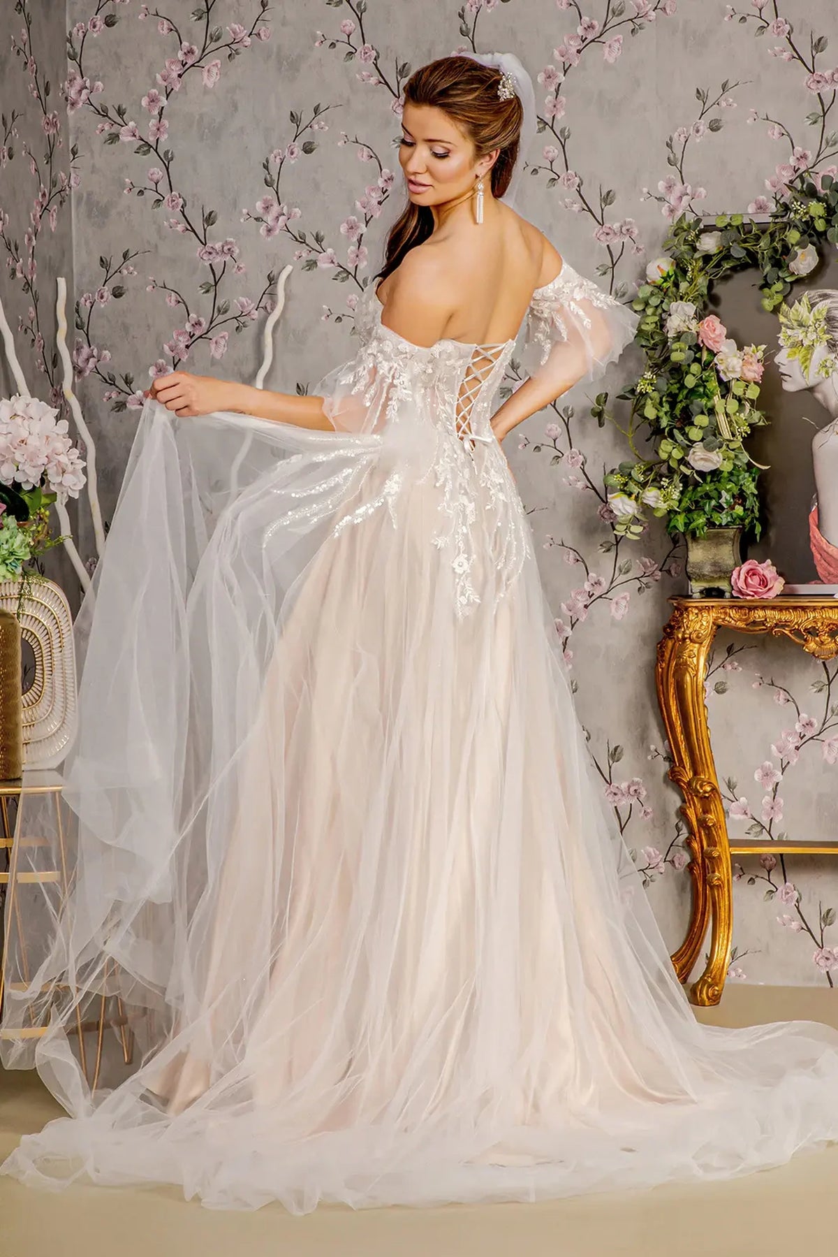 A sweeping mesh skirt flows beneath the lace-up back of this Ivory/Champagne wedding gown.