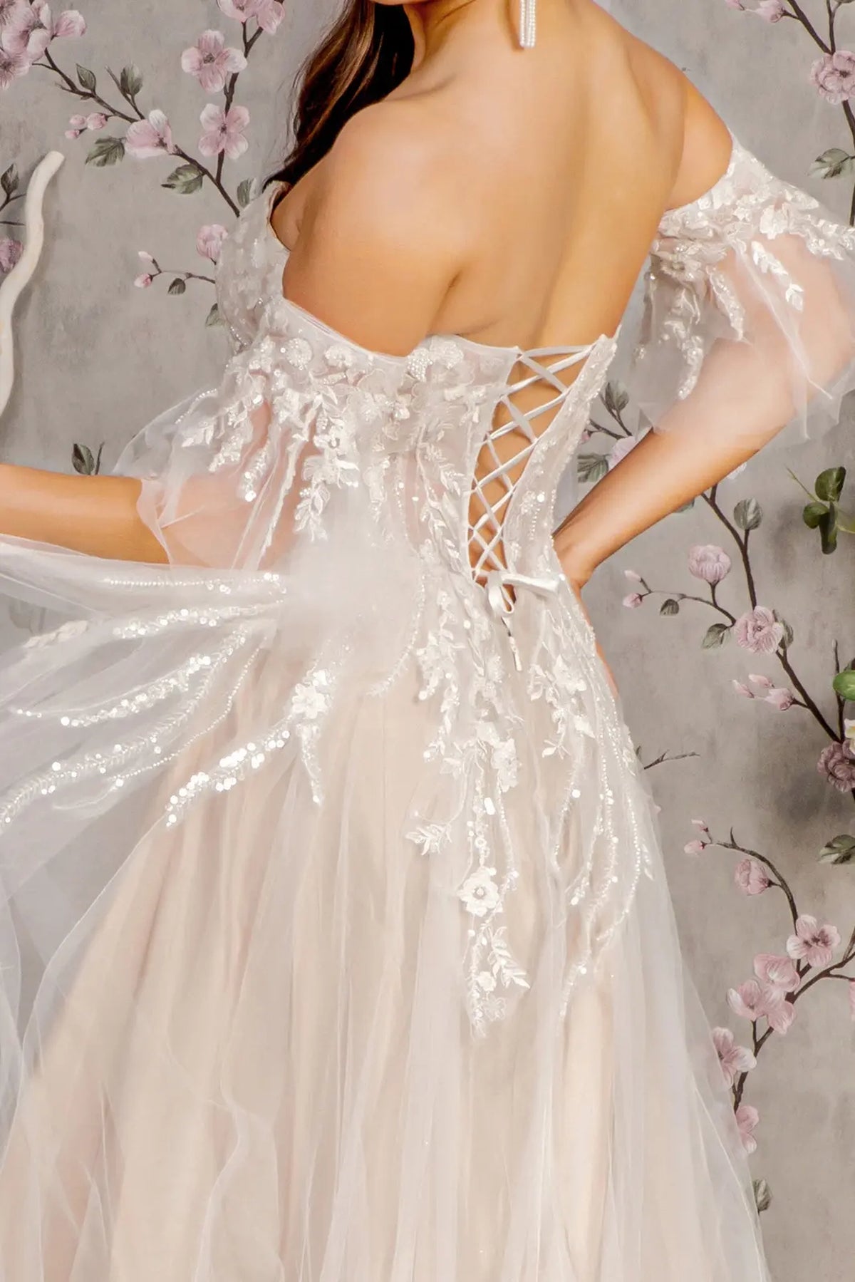 Ribbon lacing crosses the open back of this Ivory/Champagne wedding gown between embroidered sheer panels.