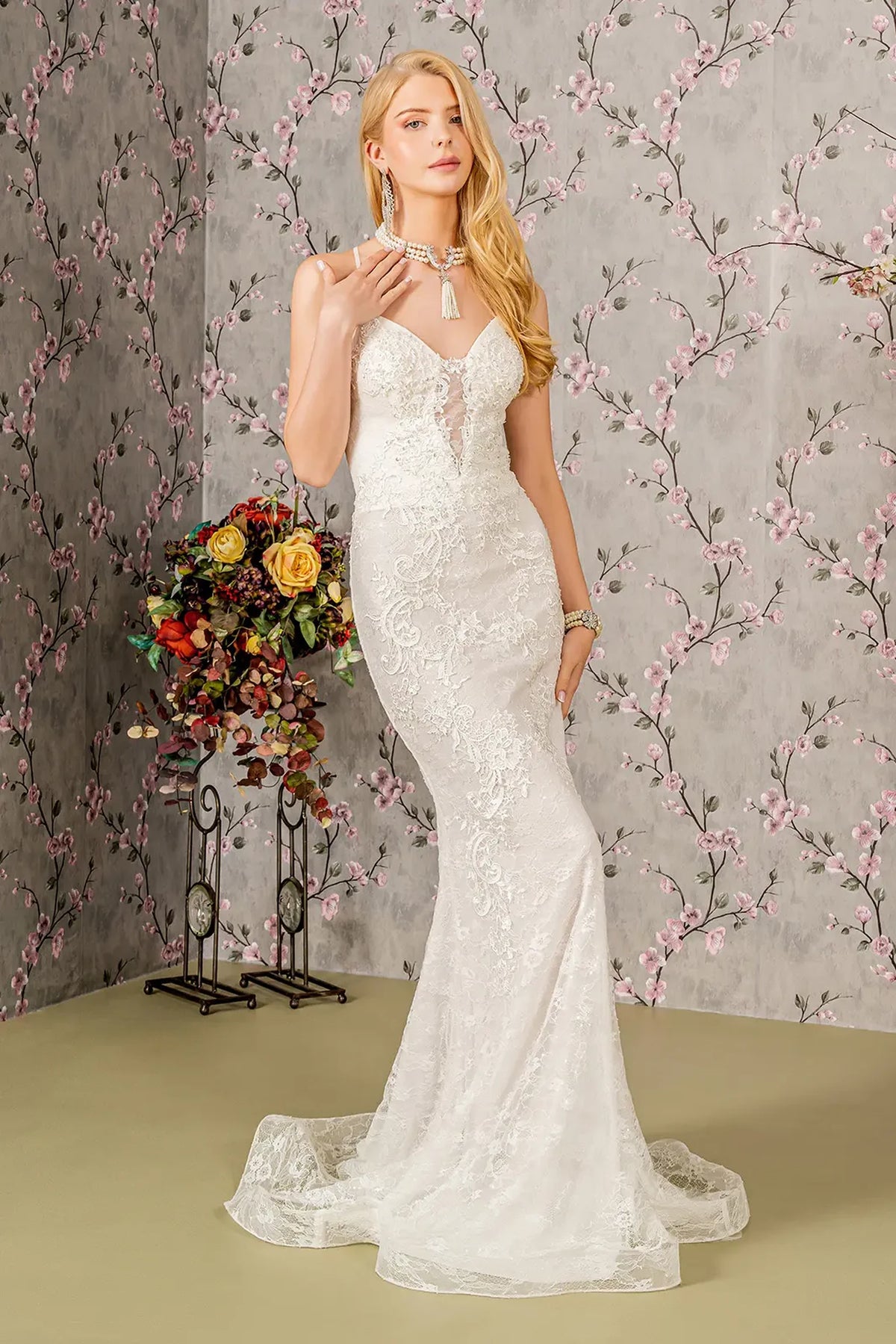 The embroidered lace skirt of this ivory wedding gown follows a fitted mermaid shape.