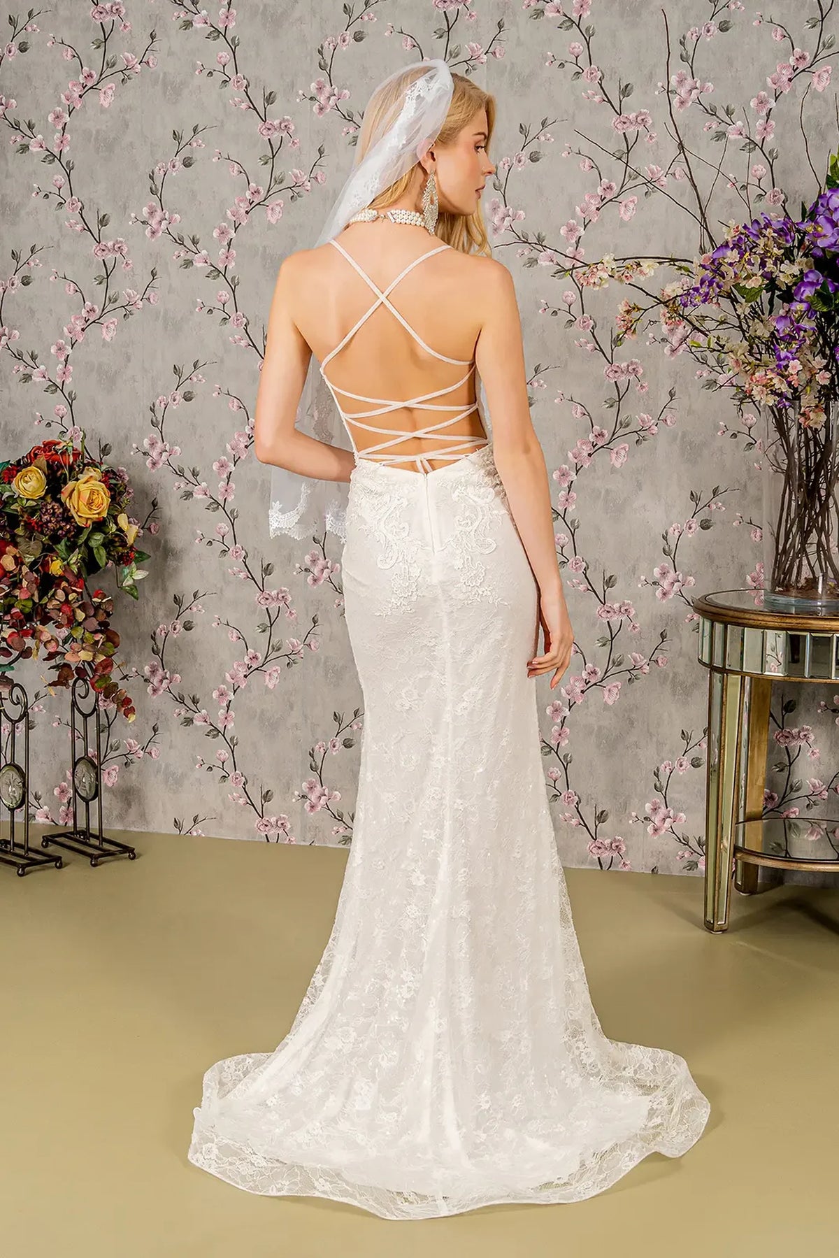 Crossed straps frame the open back above the ivory wedding gown's flared hem.