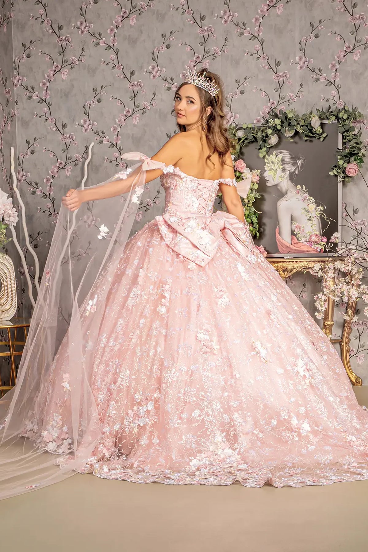 Layered skirt showcases the Blush quinceañera ball gown with detachable ribbons.