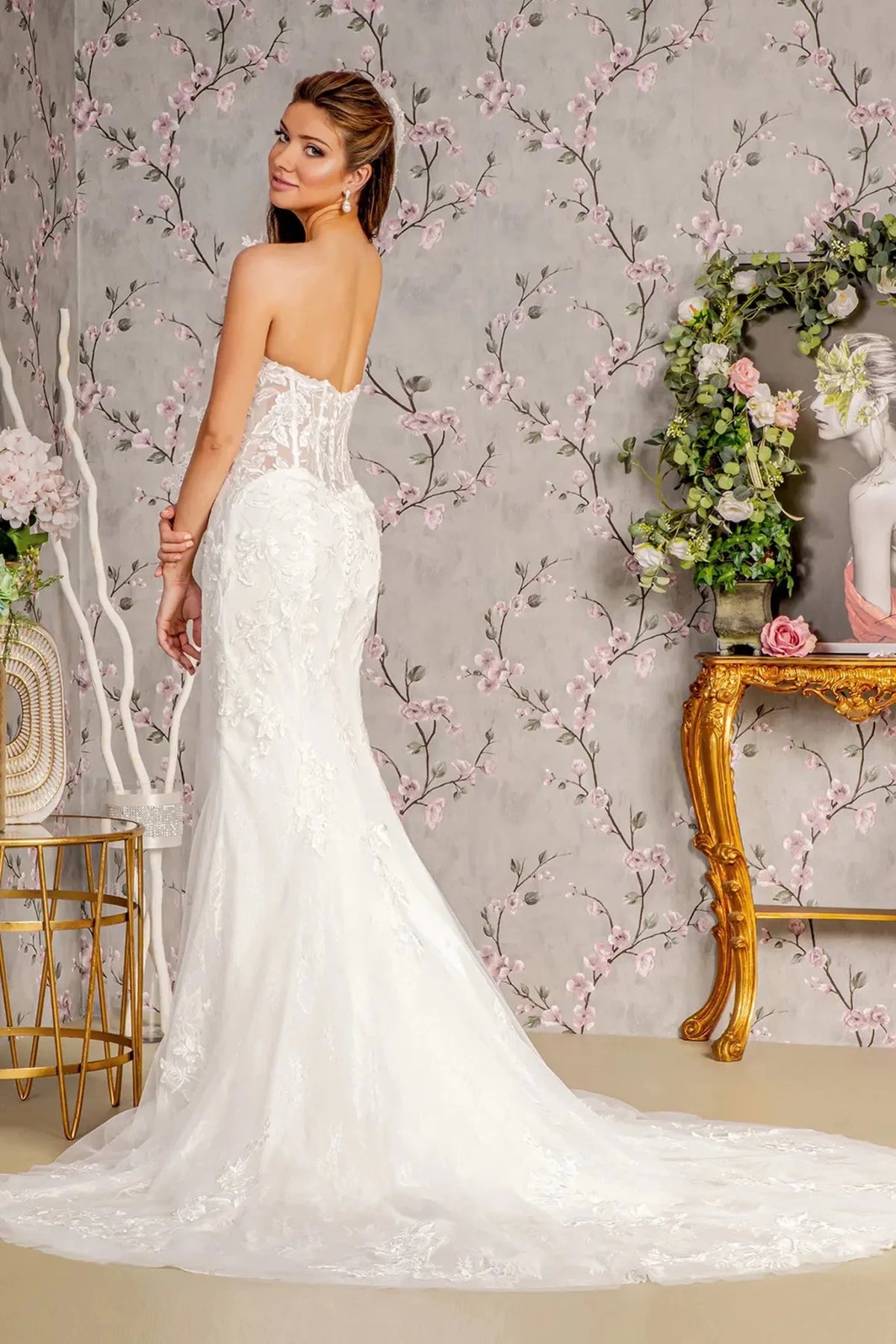 The white wedding gown's sheer low back flows into a sweeping embroidered train.
