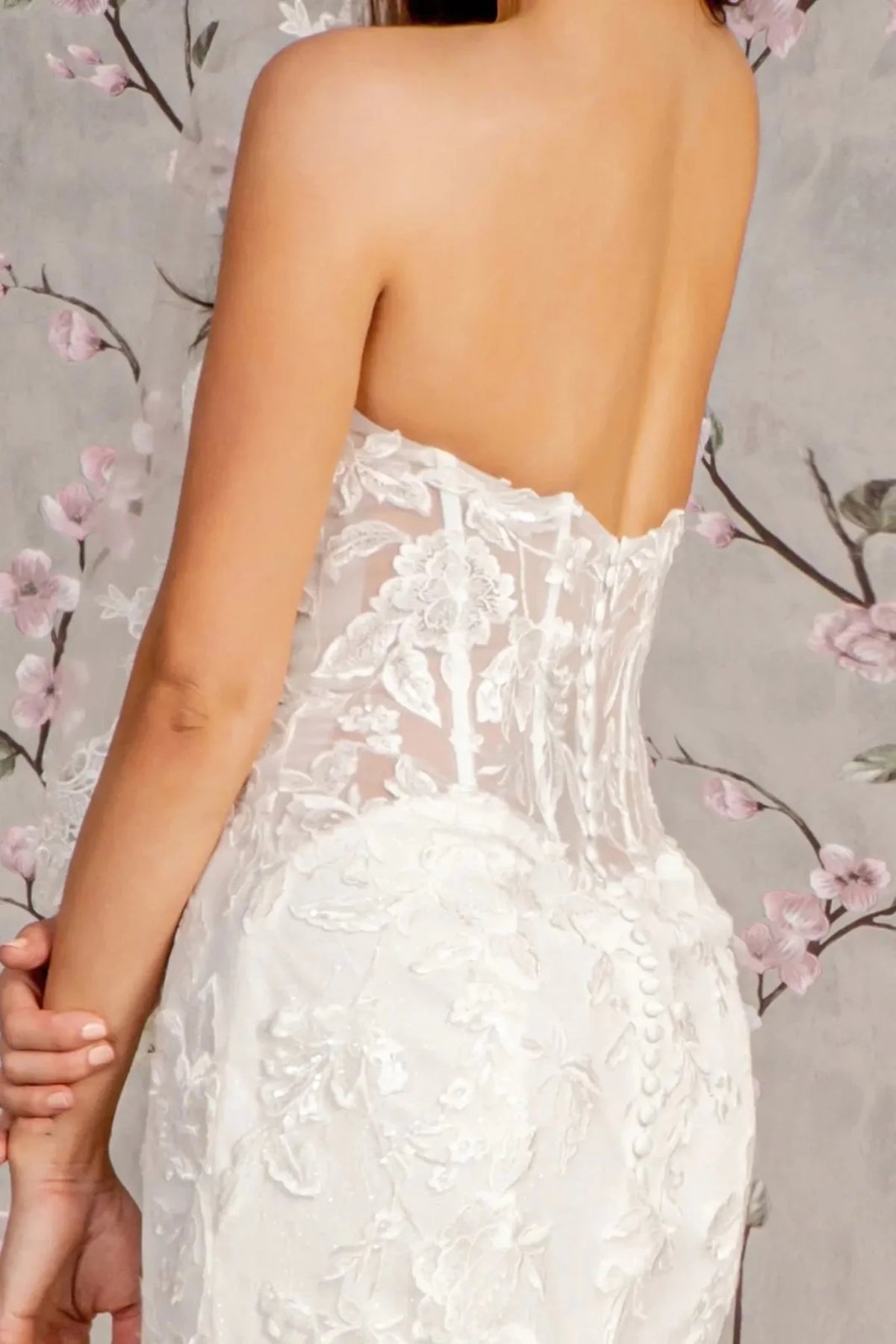 Buttons finish the sheer embroidered back panel on this white wedding gown.