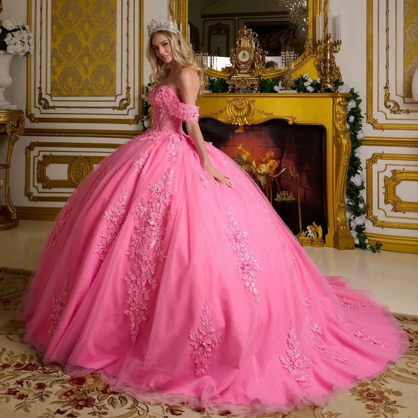 Woman in a pink gown with floral details in an ornate room.