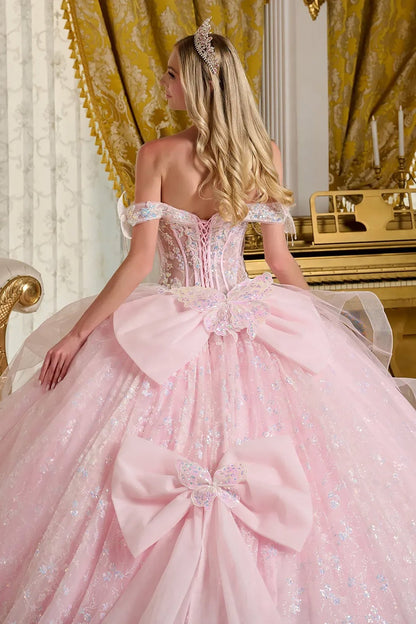 Woman in a pink ball gown with floral details with big ribbon in the back in an elegant room zoom back view.