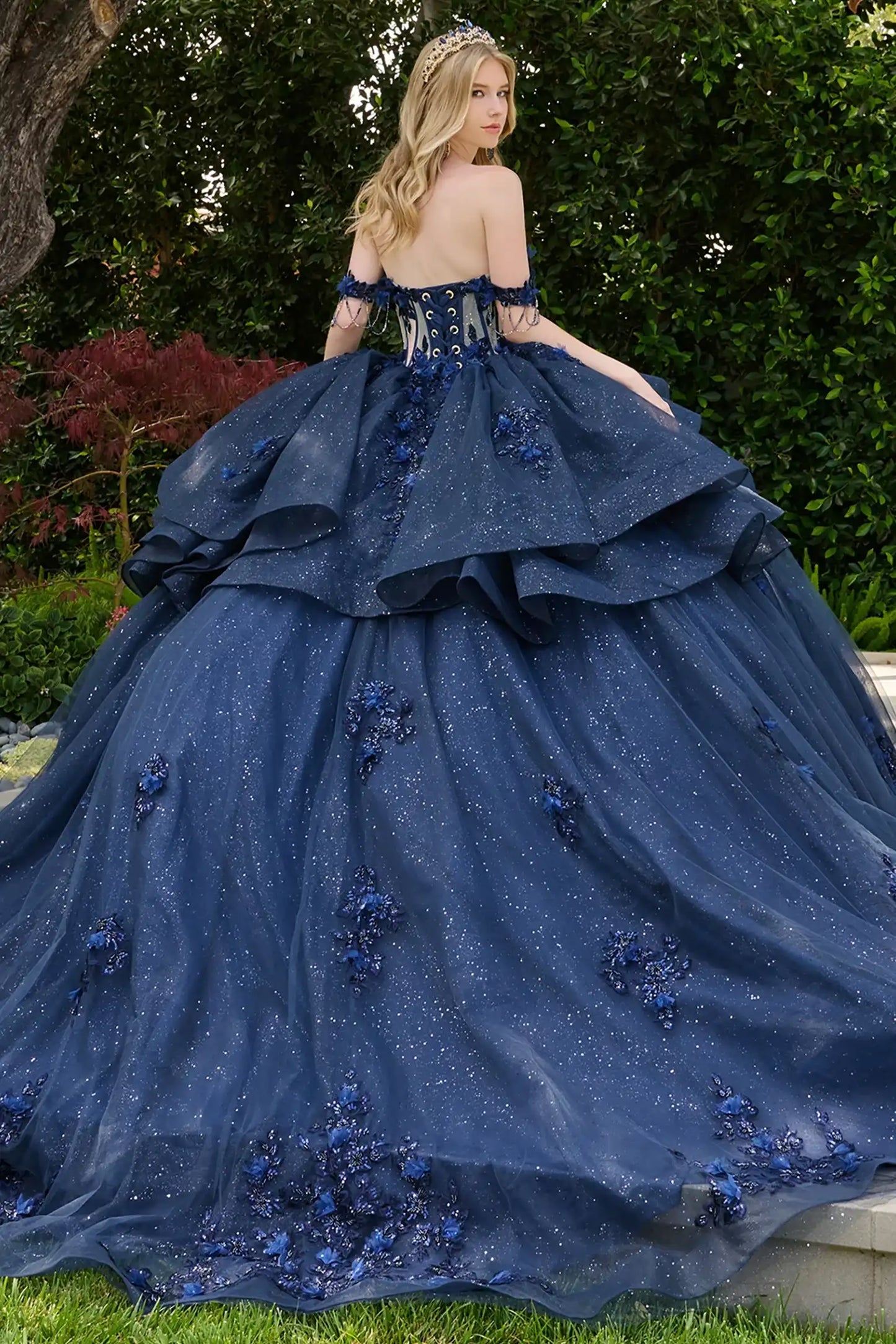 Navy quinceañera ball gown showcasing lace-up bodice with bejeweled grommets and dramatic train-length skirt