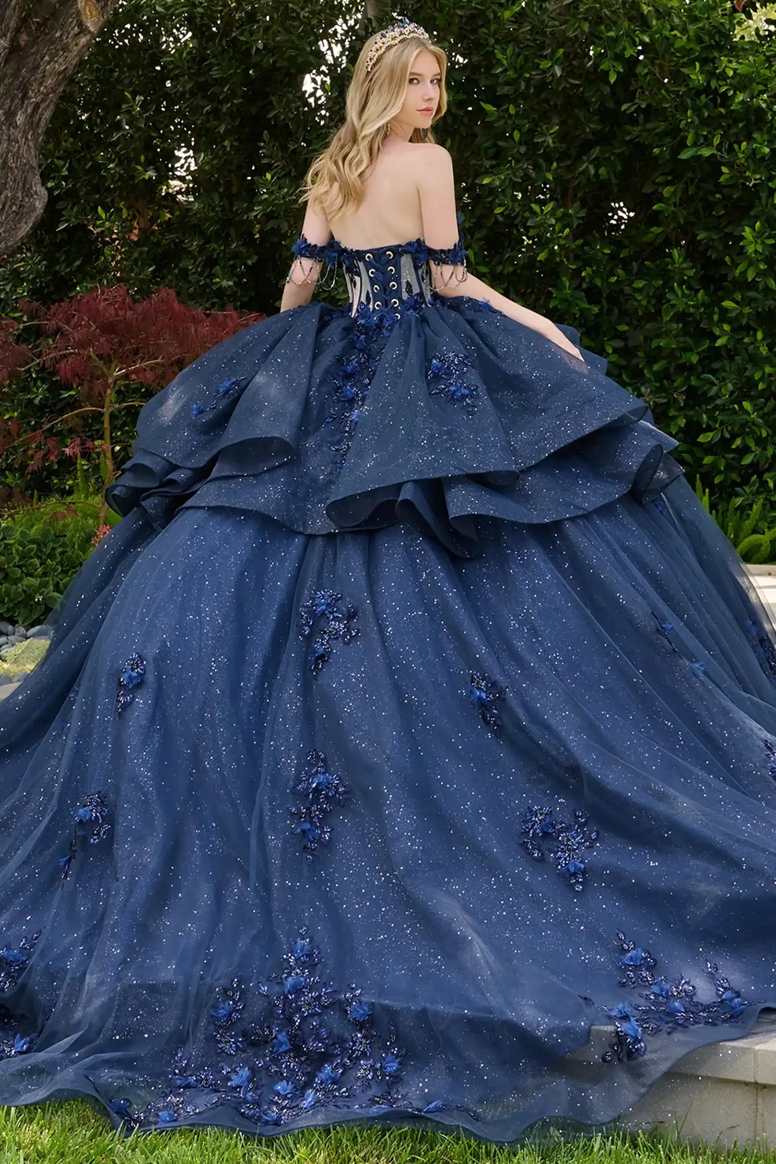 Navy quinceañera ball gown showcasing lace-up bodice with bejeweled grommets and dramatic train-length skirt