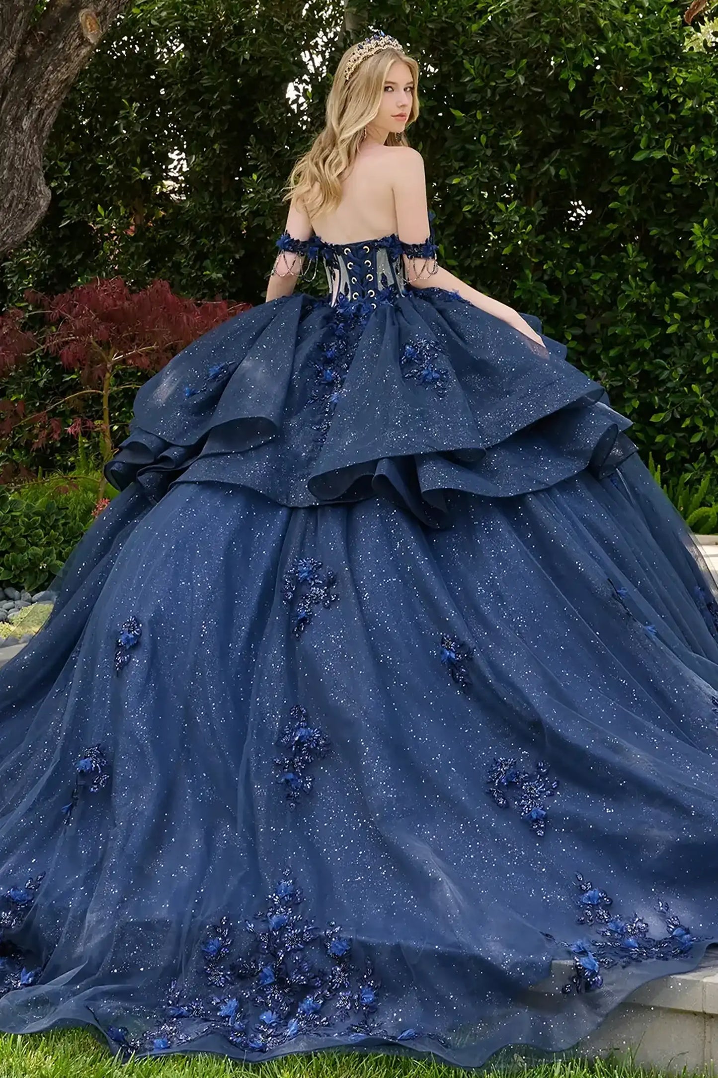 Navy quinceañera ball gown showcasing lace-up bodice with bejeweled grommets and dramatic glitter overskirt train-length skirt