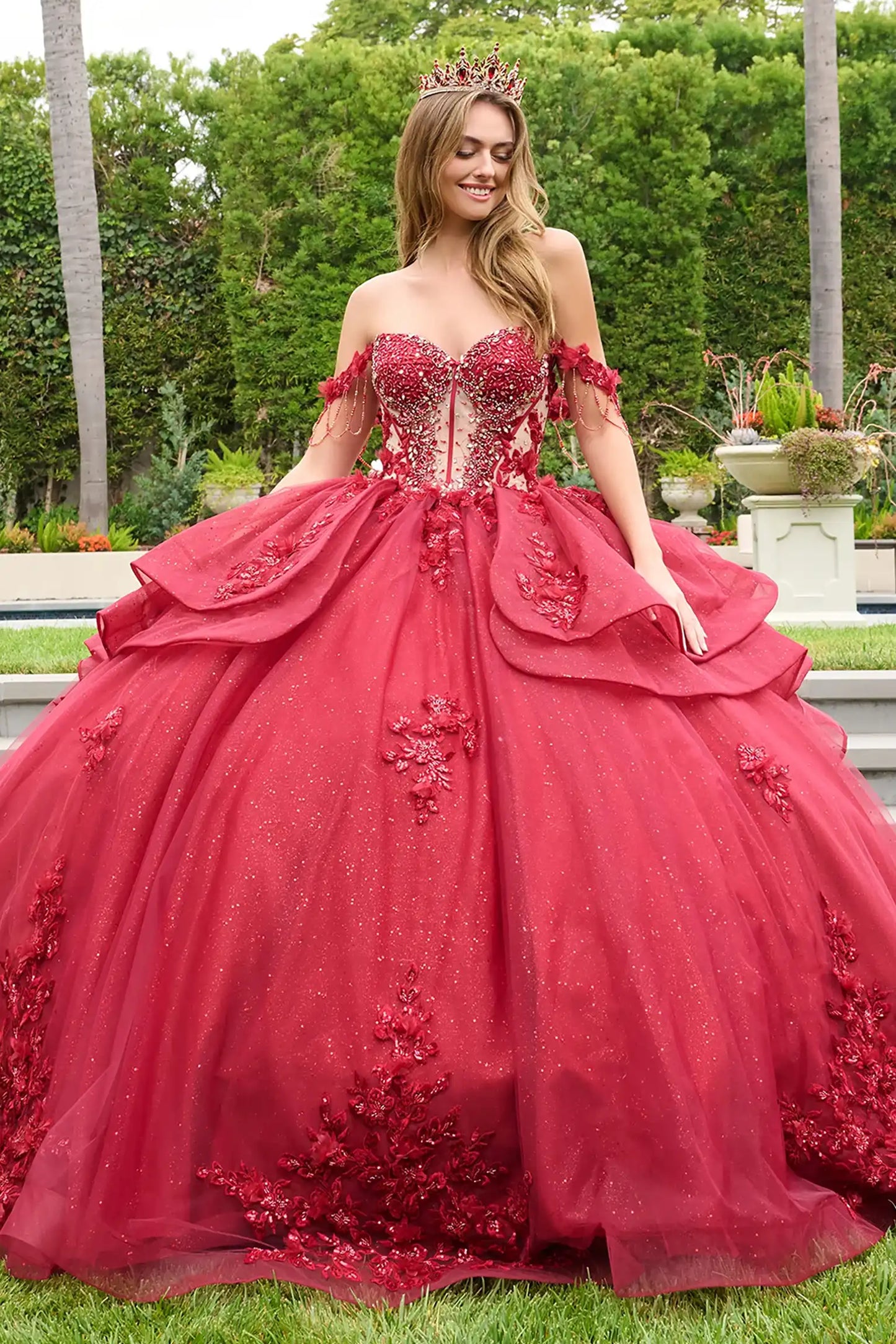 Red quinceañera ball gown featuring jeweled embroidery, detachable off-shoulder straps beaded fringe and glitter overskirts