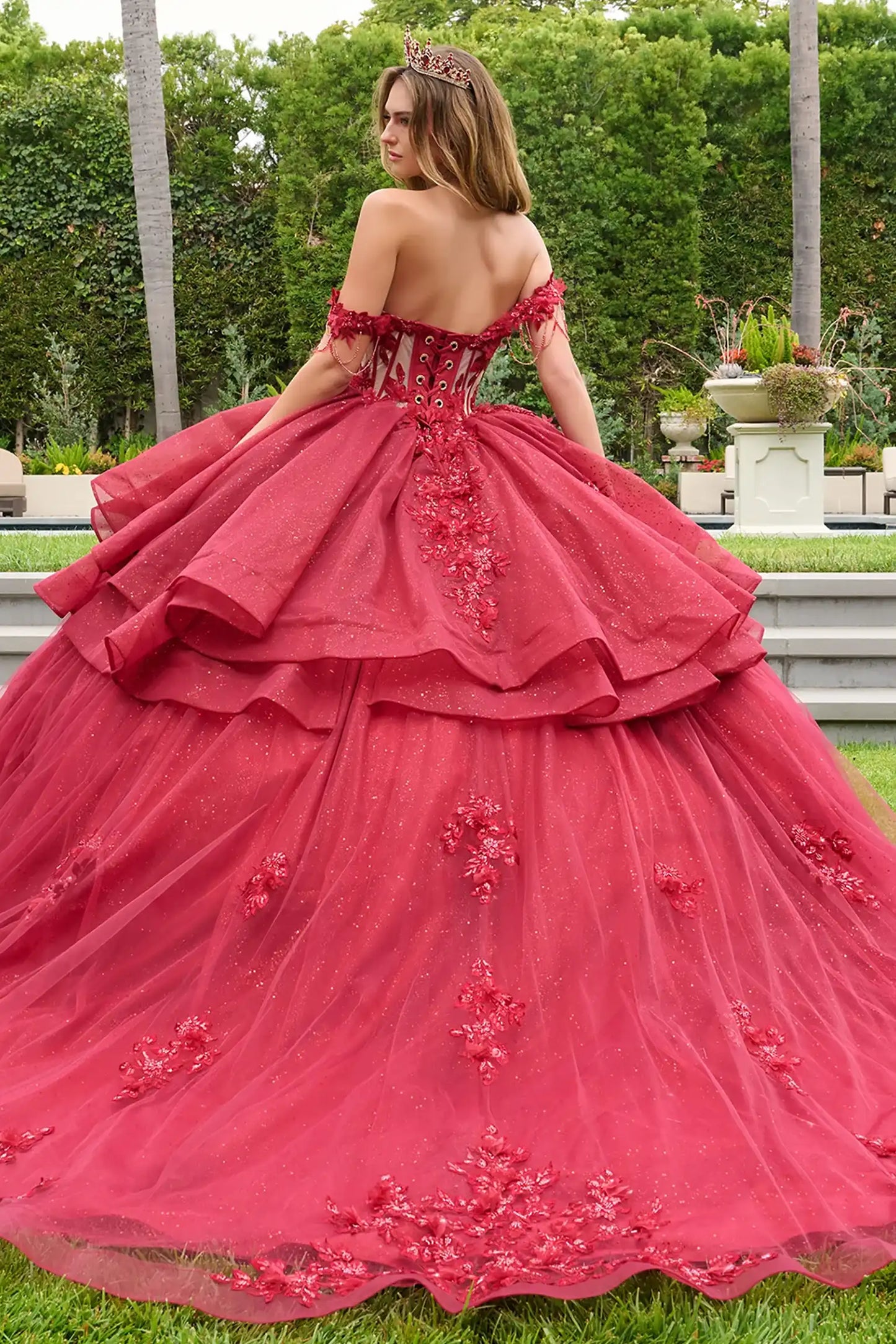 Red quinceañera ball gown showcasing lace-up bodice with bejeweled grommets and dramatic train-length skirt