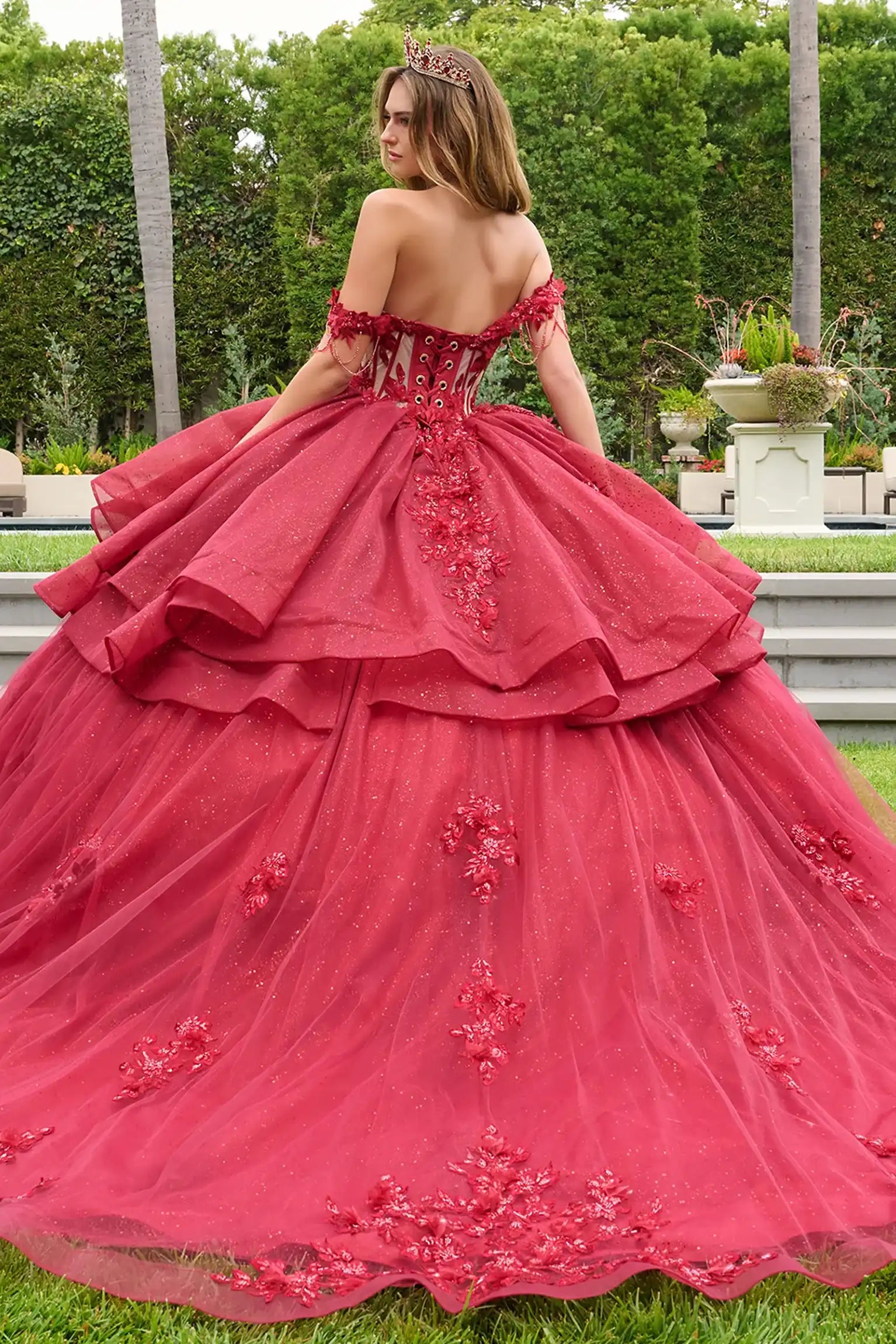 Red quinceañera ball gown showcasing lace-up bodice with bejeweled grommets and dramatic train-length skirt