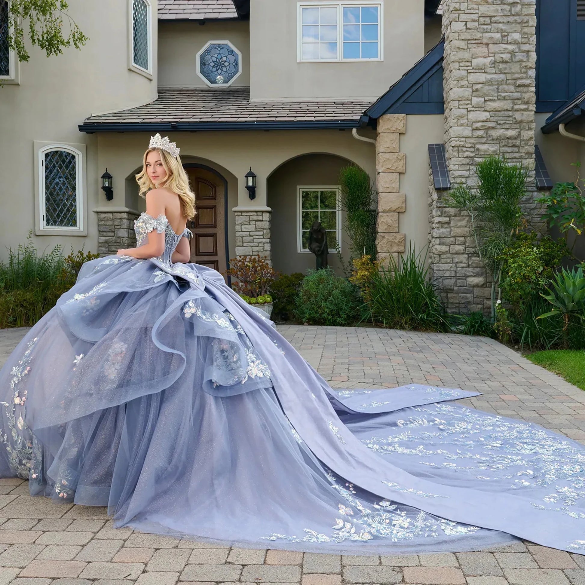 Woman in a blue floral gown standing in front of a house