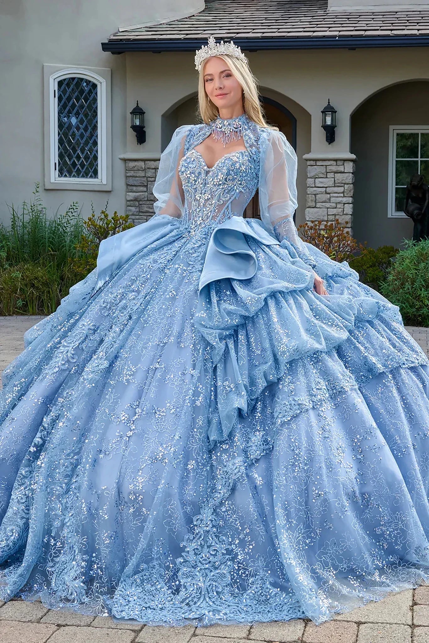 Woman in a blue ball gown standing in front of a house.