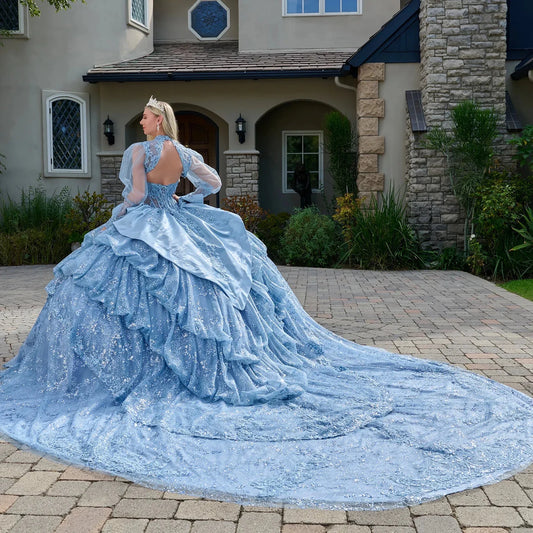 Woman in a blue ball gown standing in front of a house.