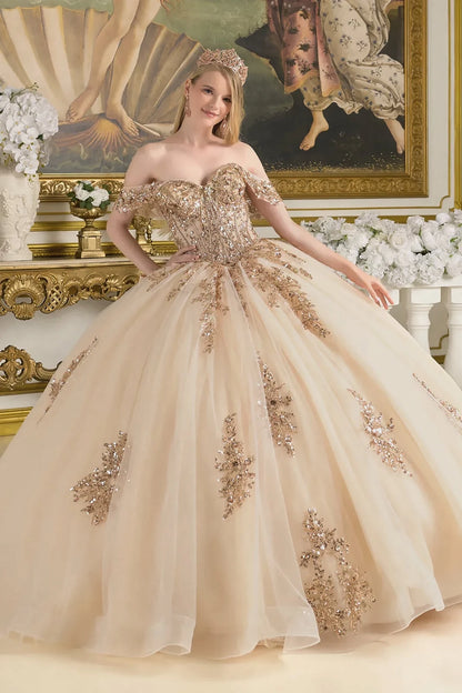 Woman in a champagne quince gown standing in an elegant room with floral decorations.