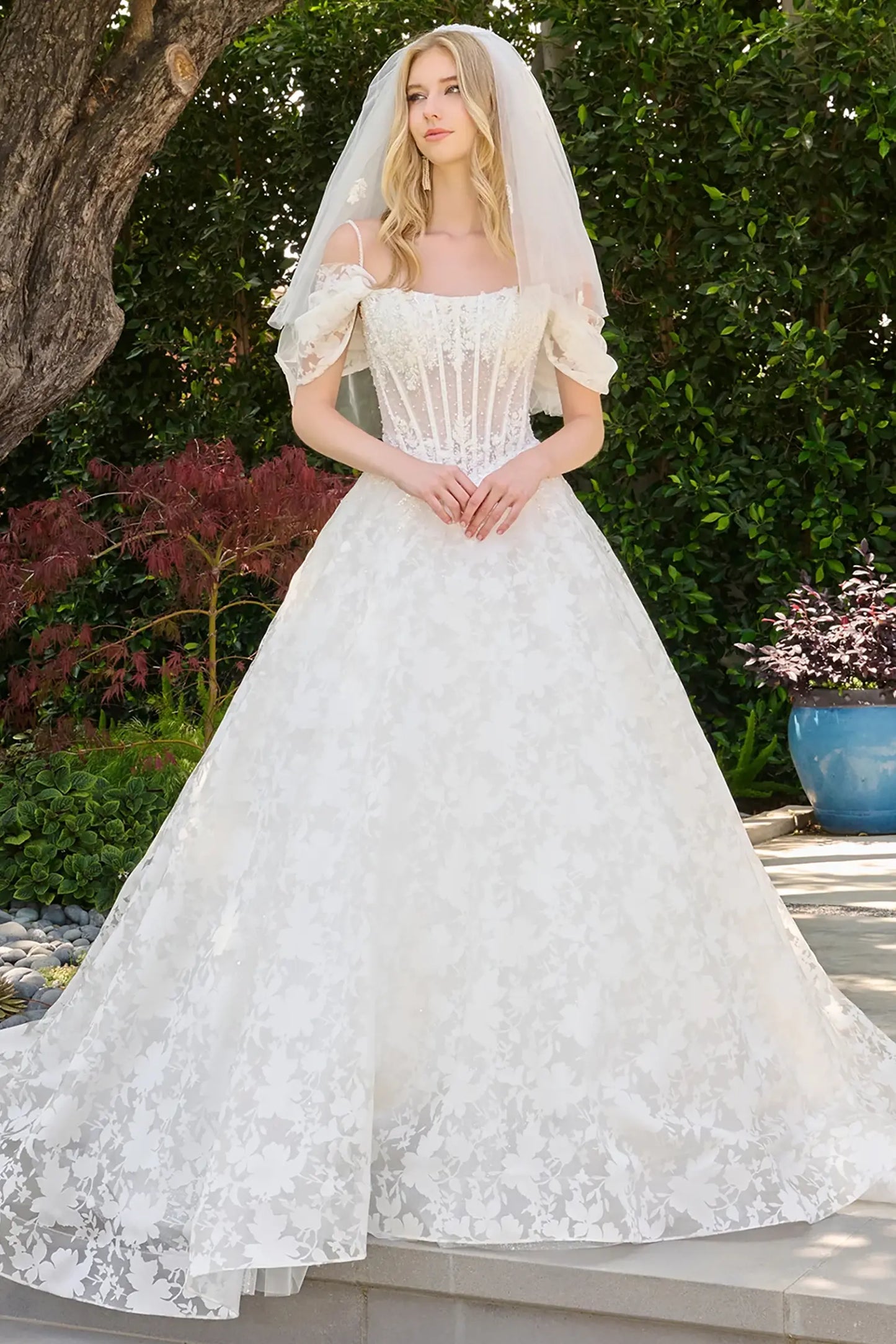 Off-white wedding dress with boat neckline and cold-shoulder design featuring detachable pleated straps