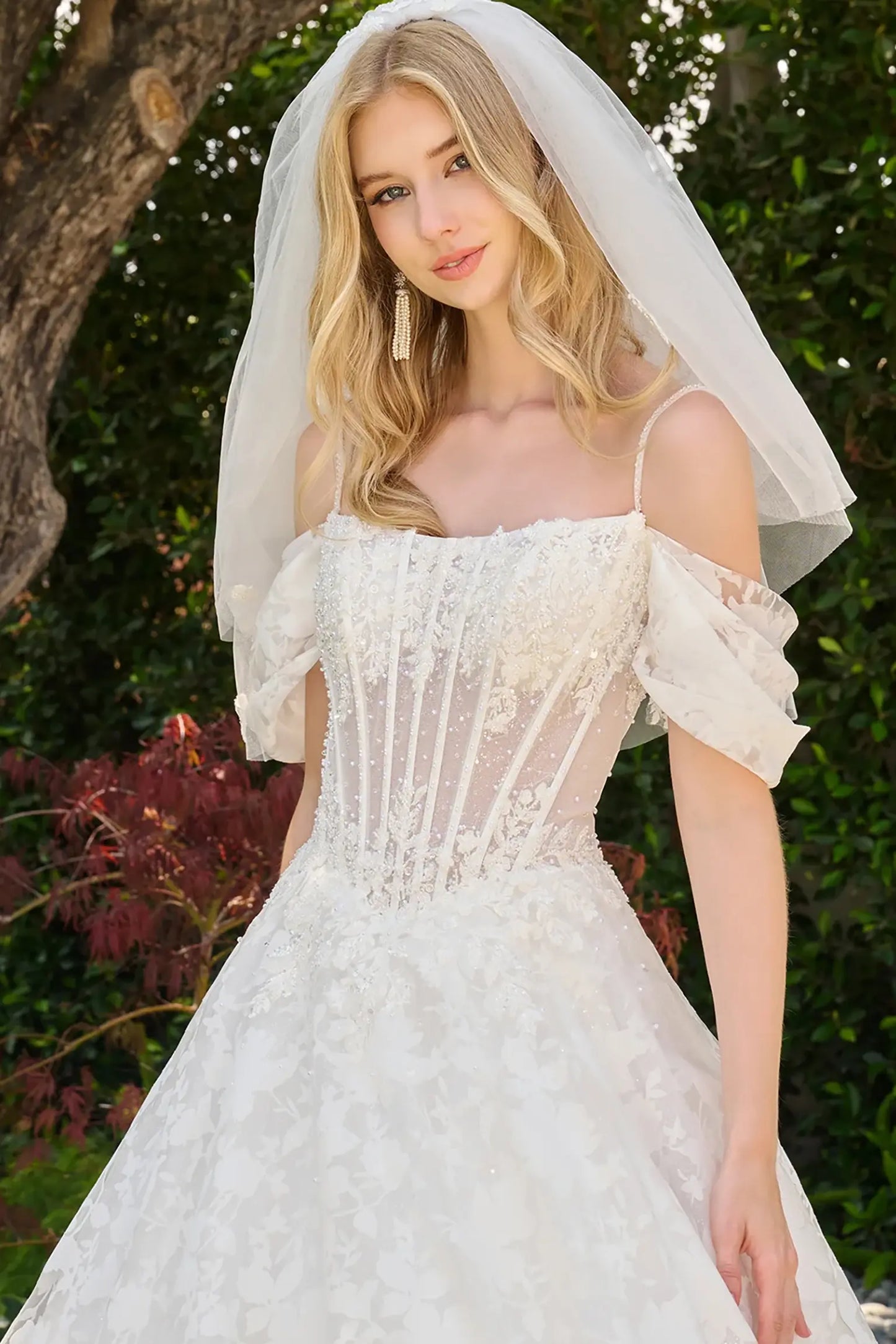 Off-white wedding dress completed with short veil coordinating with cold off shoulder sleeves