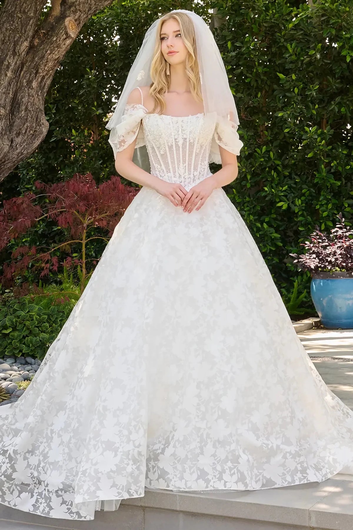 Off-white wedding dress with boat neckline and cold-shoulder design featuring detachable pleated straps