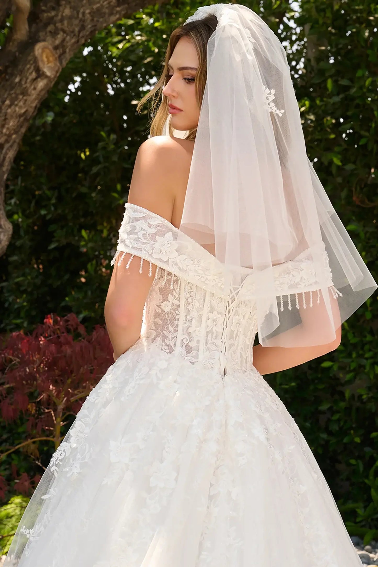Off-white wedding dress completed with short veil coordinating with the gown design and lace back up