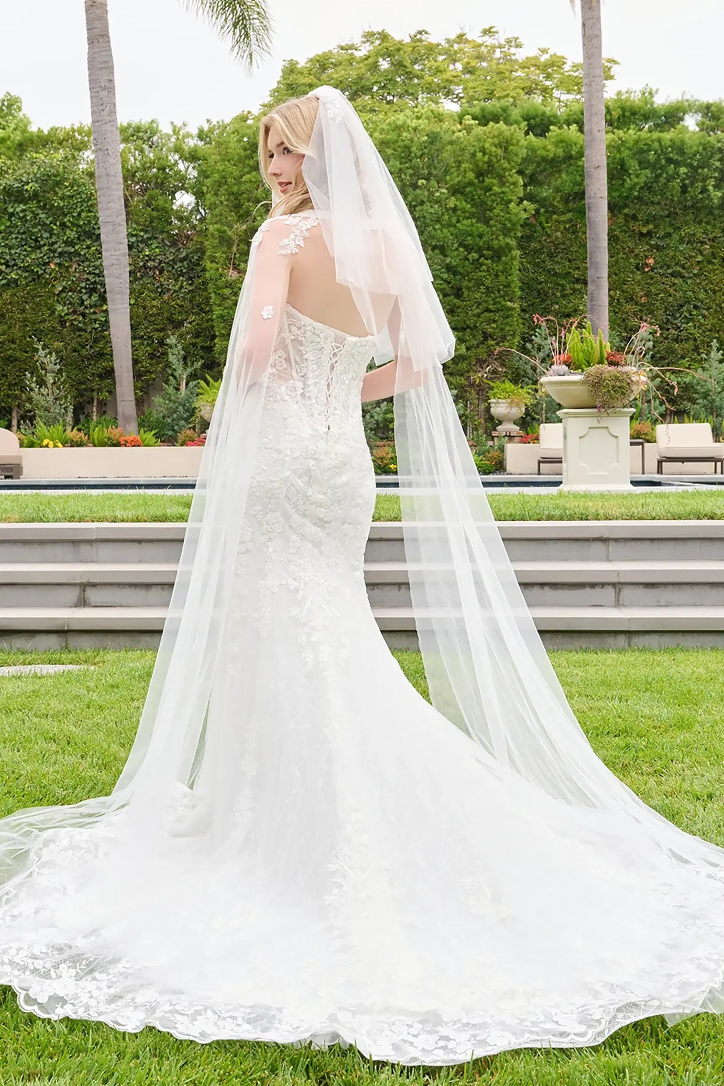 Off-white wedding dress adorned with floral embroidery extending through bodice and skirt with detachable cape