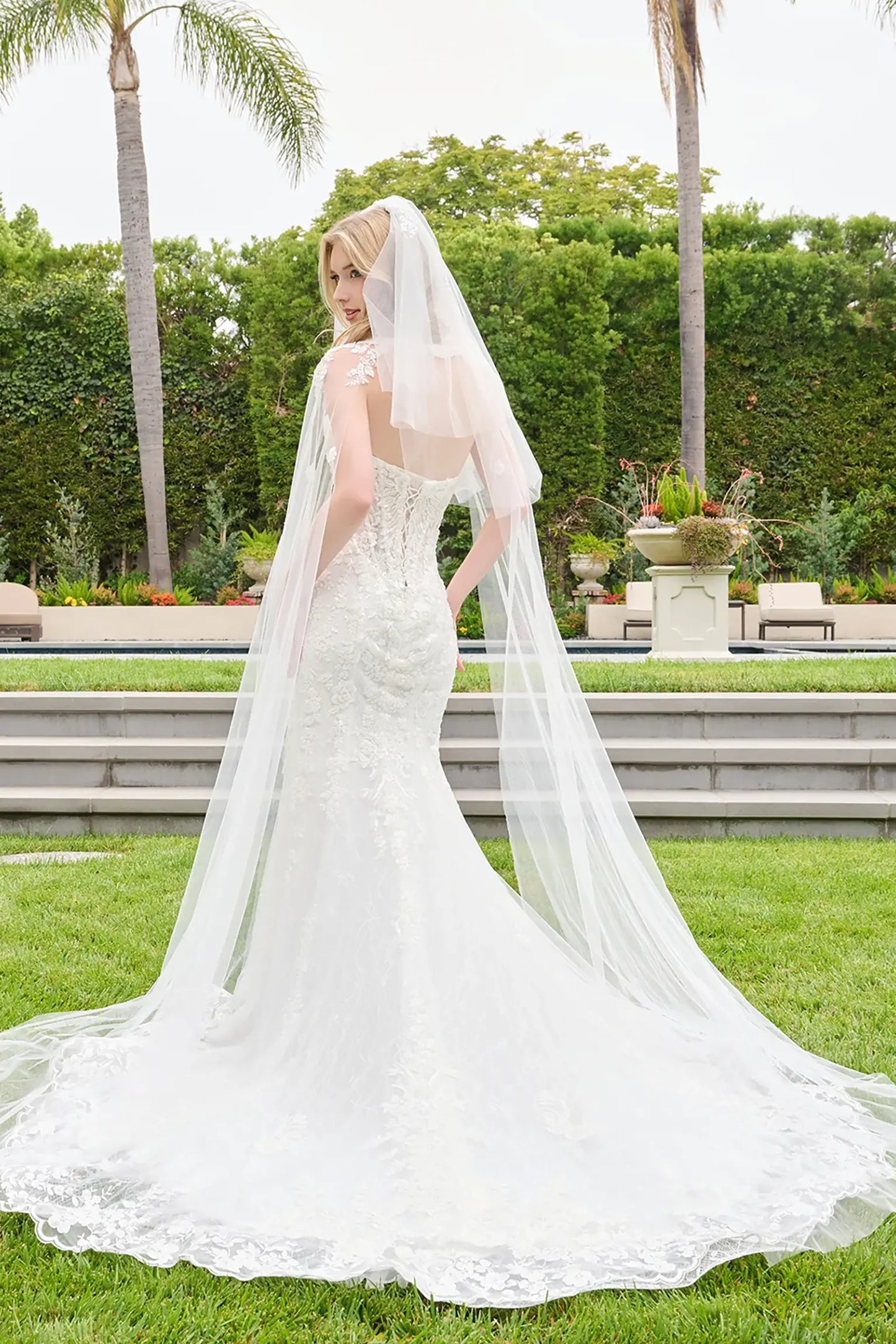 Off-white wedding dress with scalloped embroidery tracing hem and flowing into train and lace back up